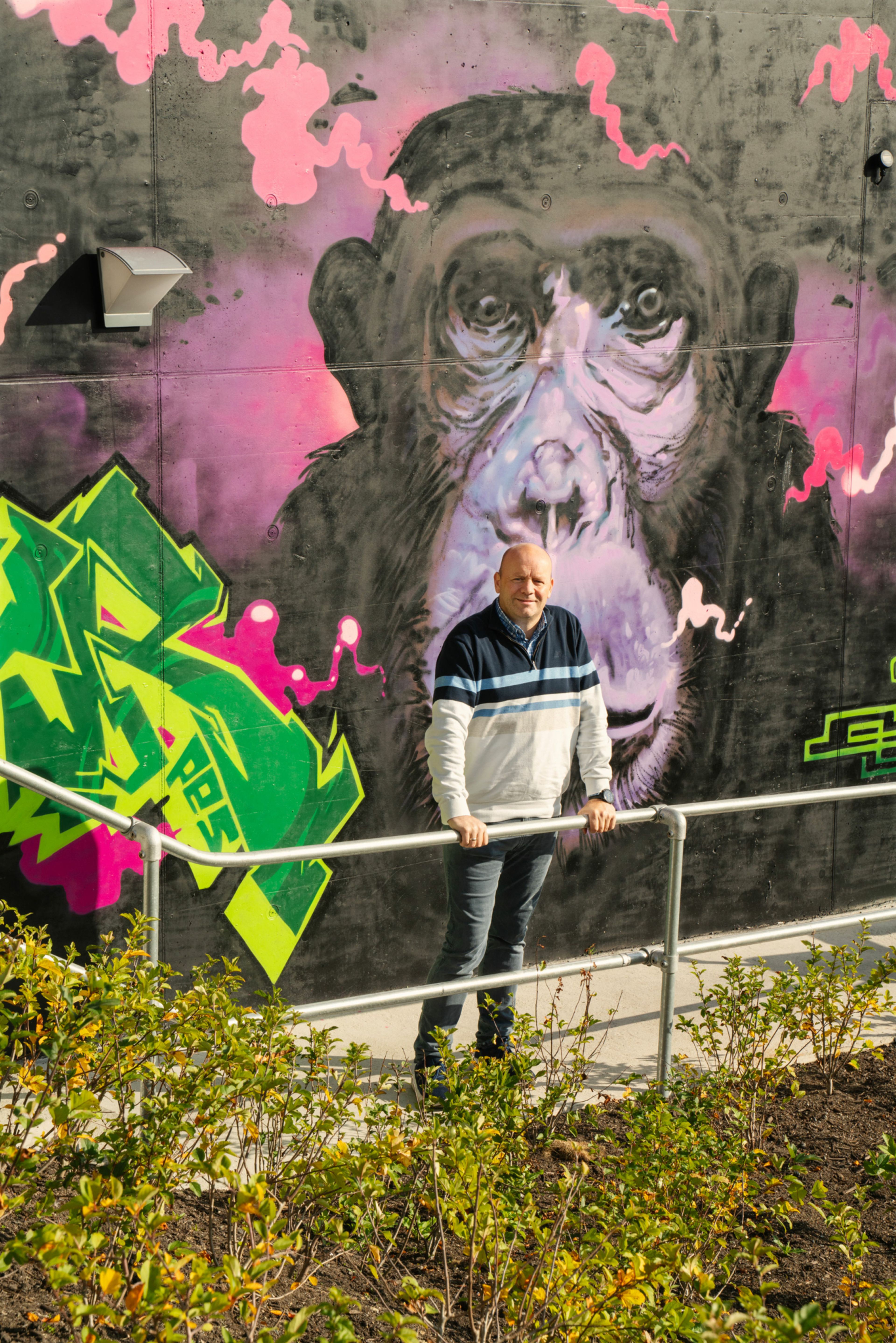 Foto av Ole Morten som står foran en del av grafittiveggen, her av en stor sjimpanse.