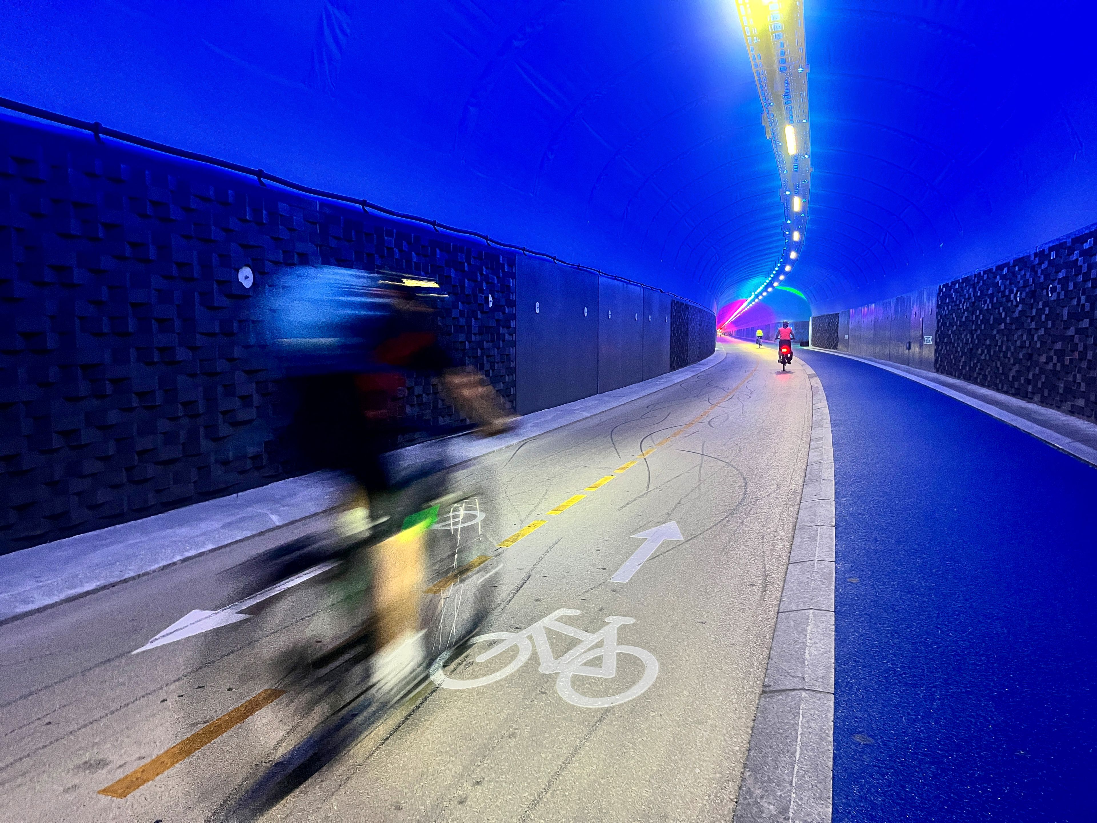 Syklist sykler på sykkelfeltet i opplyst tunnel.