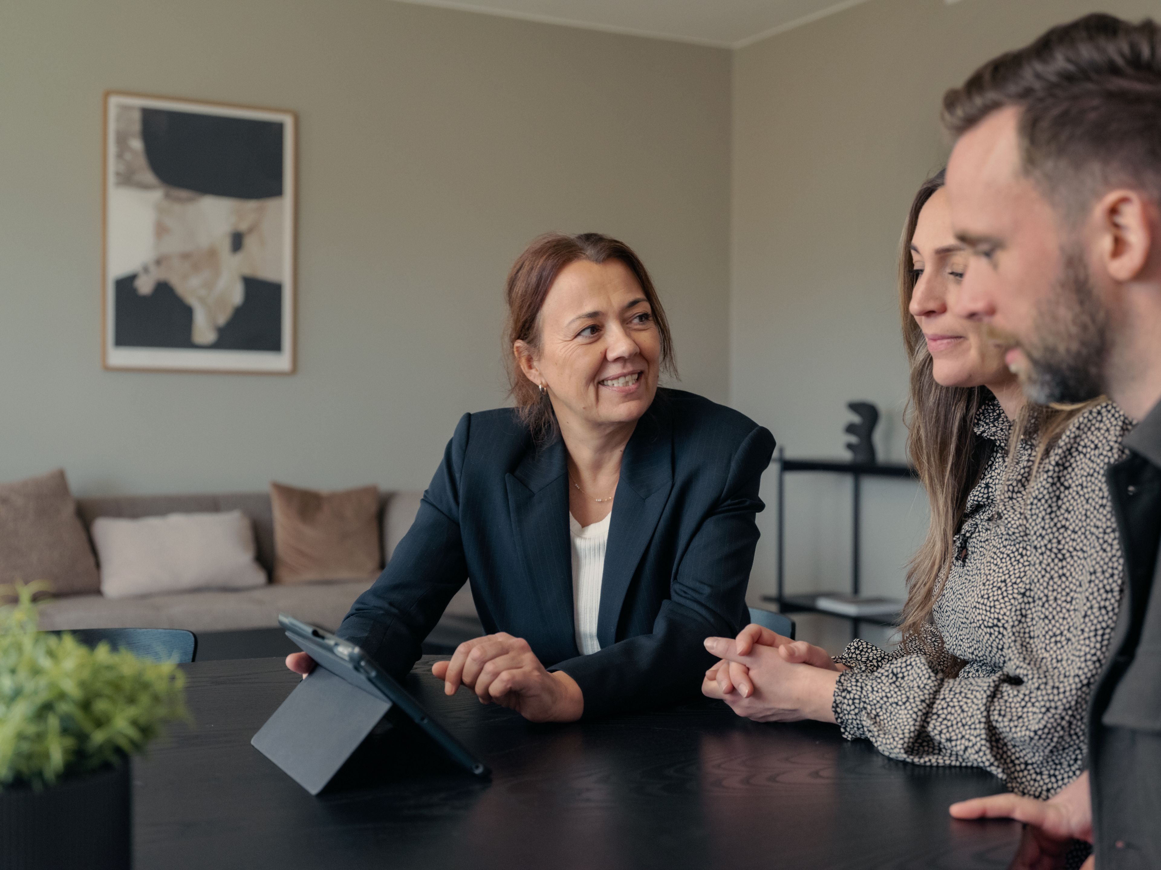 Tre personer sitter ved et bord og ser på en ipad.