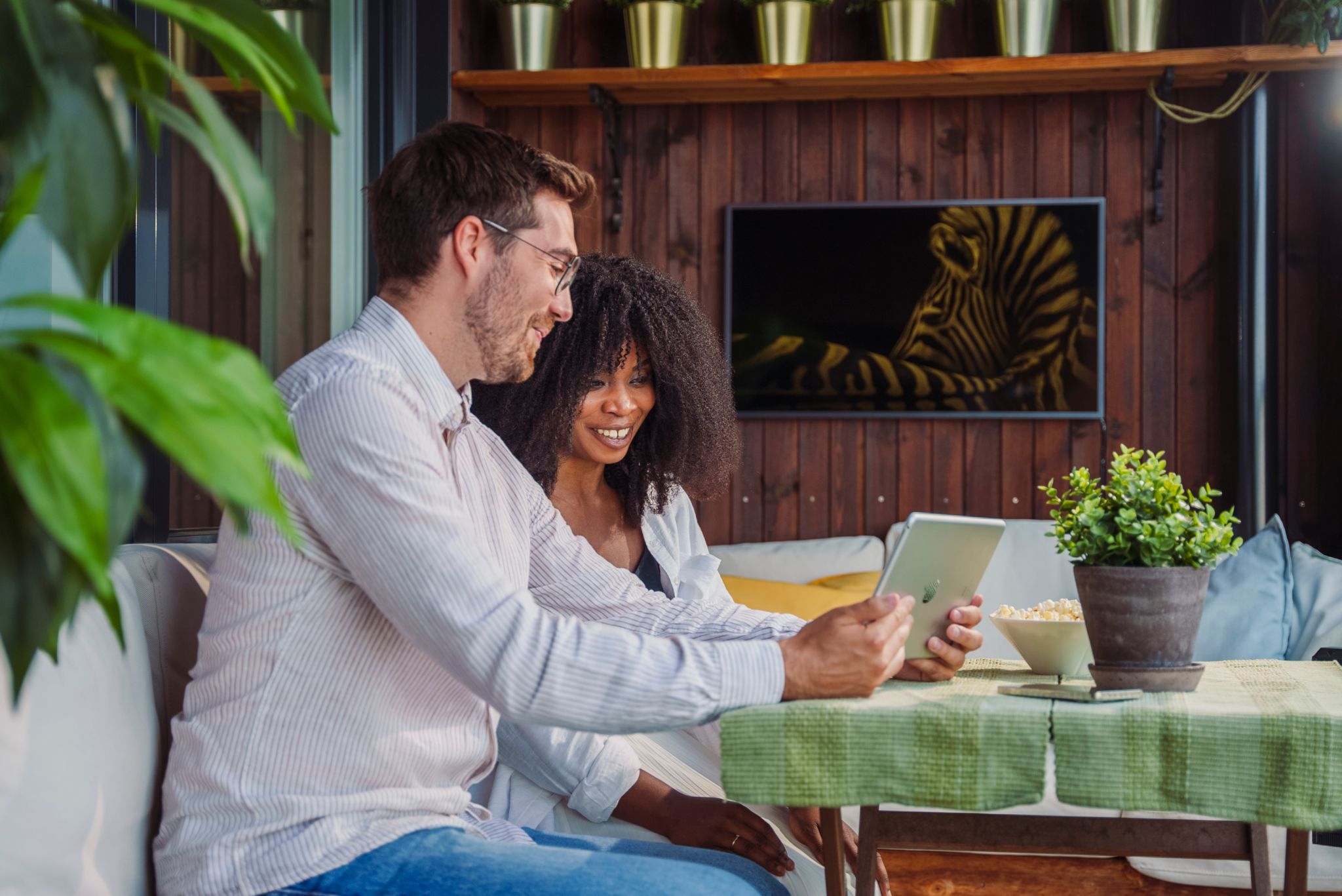 En mann og en dame sitter ved et bord og ser på en iPad sammen.