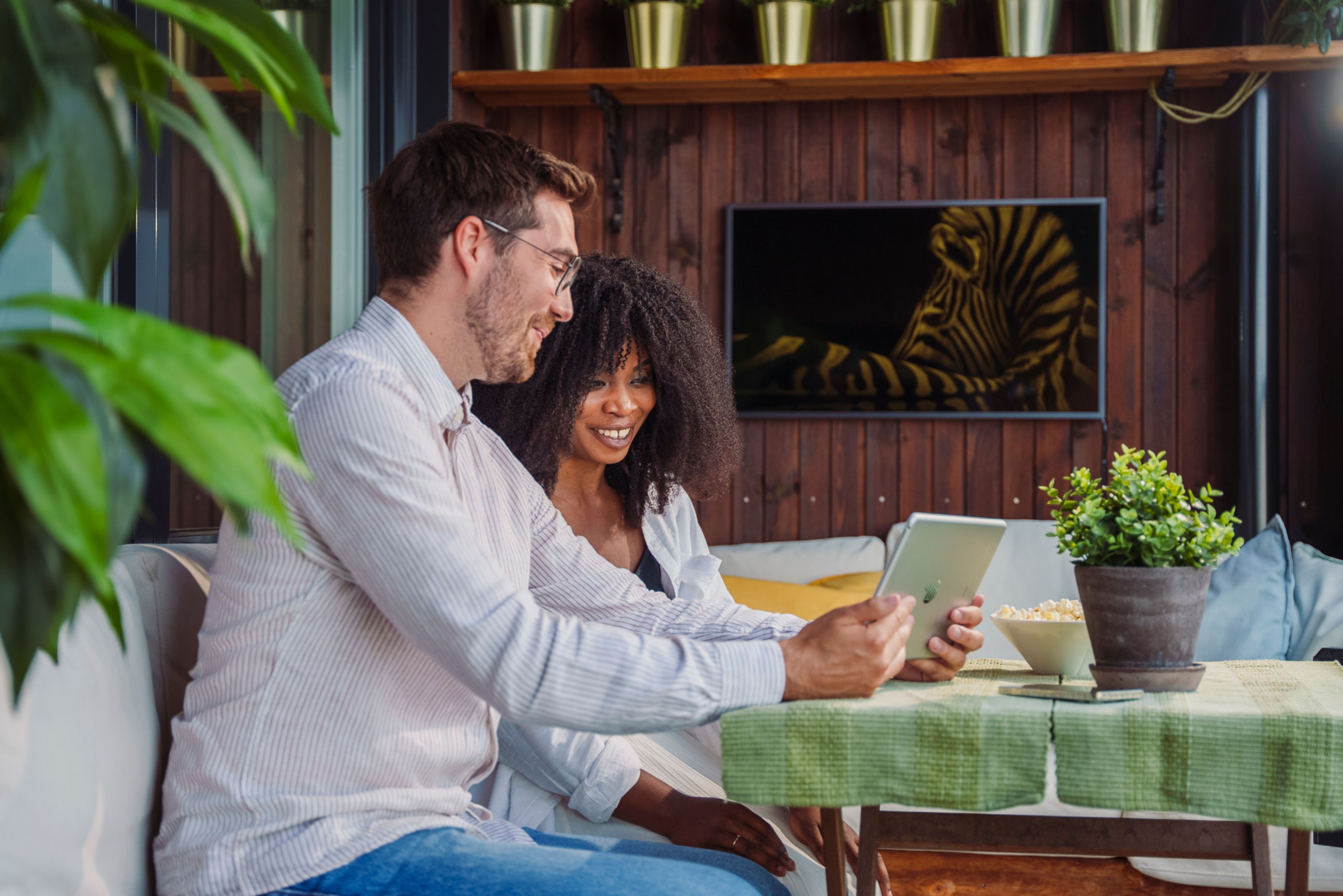 En mann og en dame sitter ved et bord og ser på en iPad sammen.