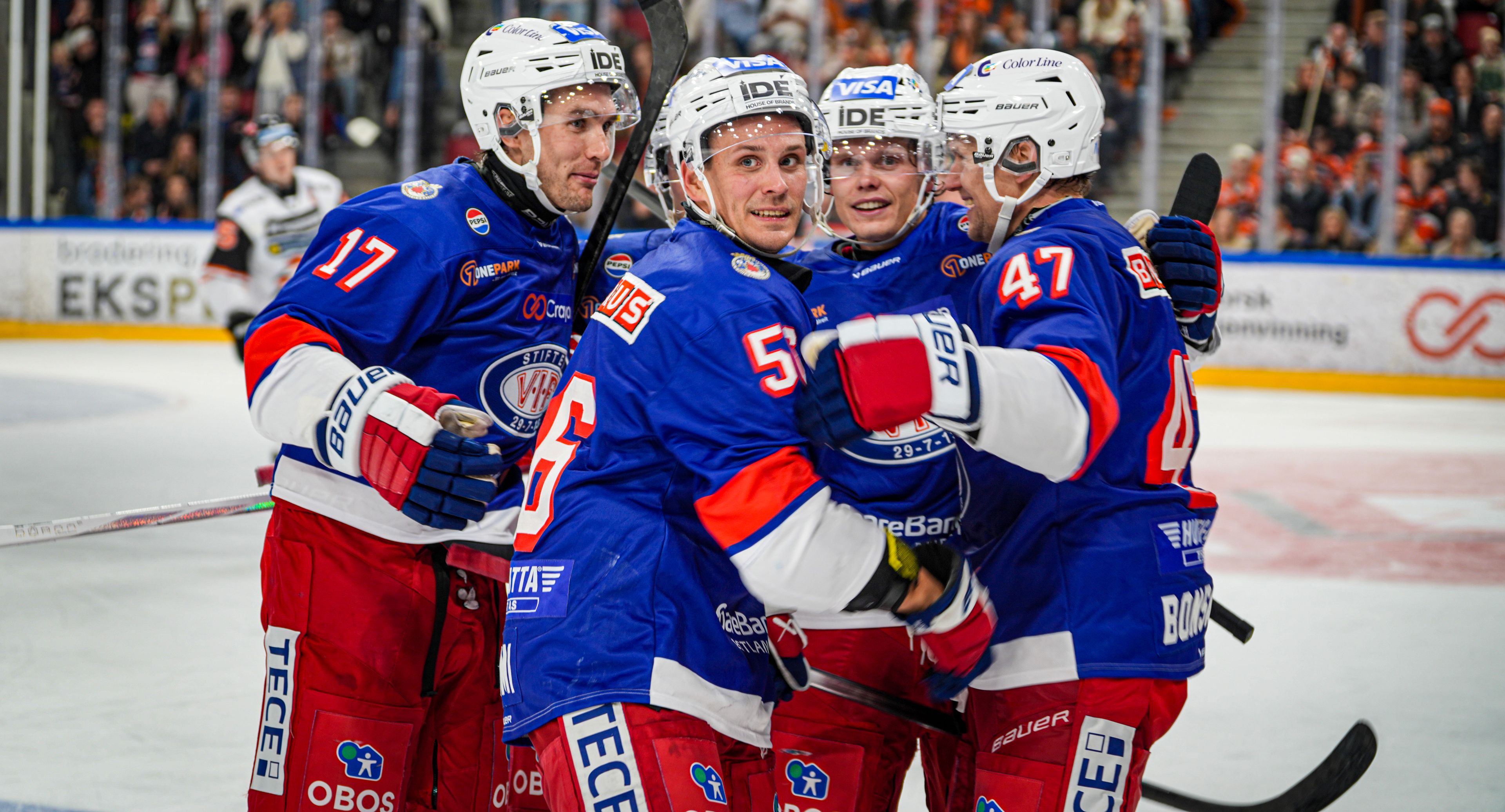 Foto av vålerenga ishockey spillere på isen, beskjært i toppen.
