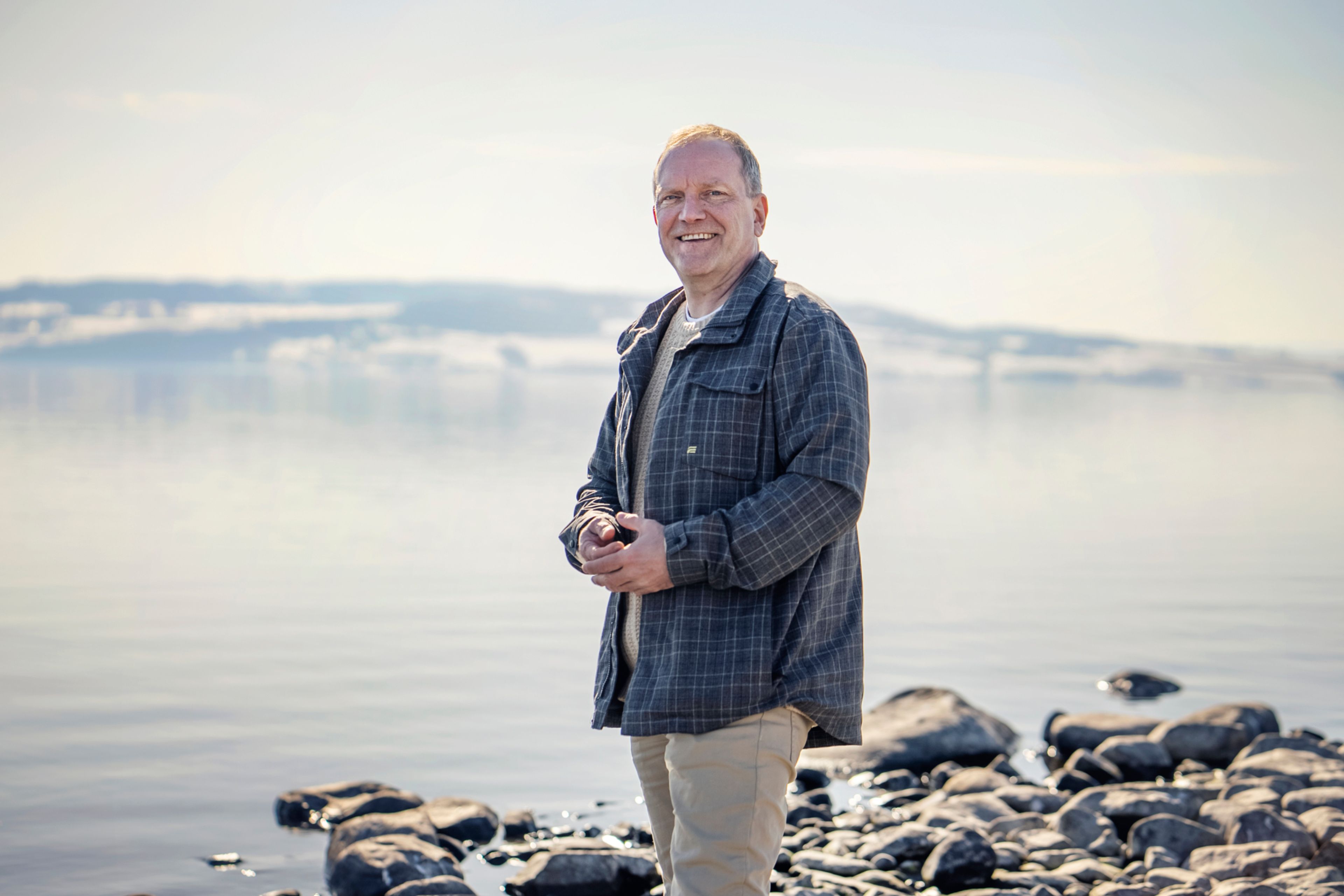 Remo Martinesen smiler mot kameraet med Mjøsa i bakgrunnen