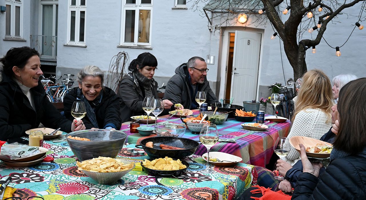 Folkene som har vært på dugnad sitter rundt et bord og spiser sammen.