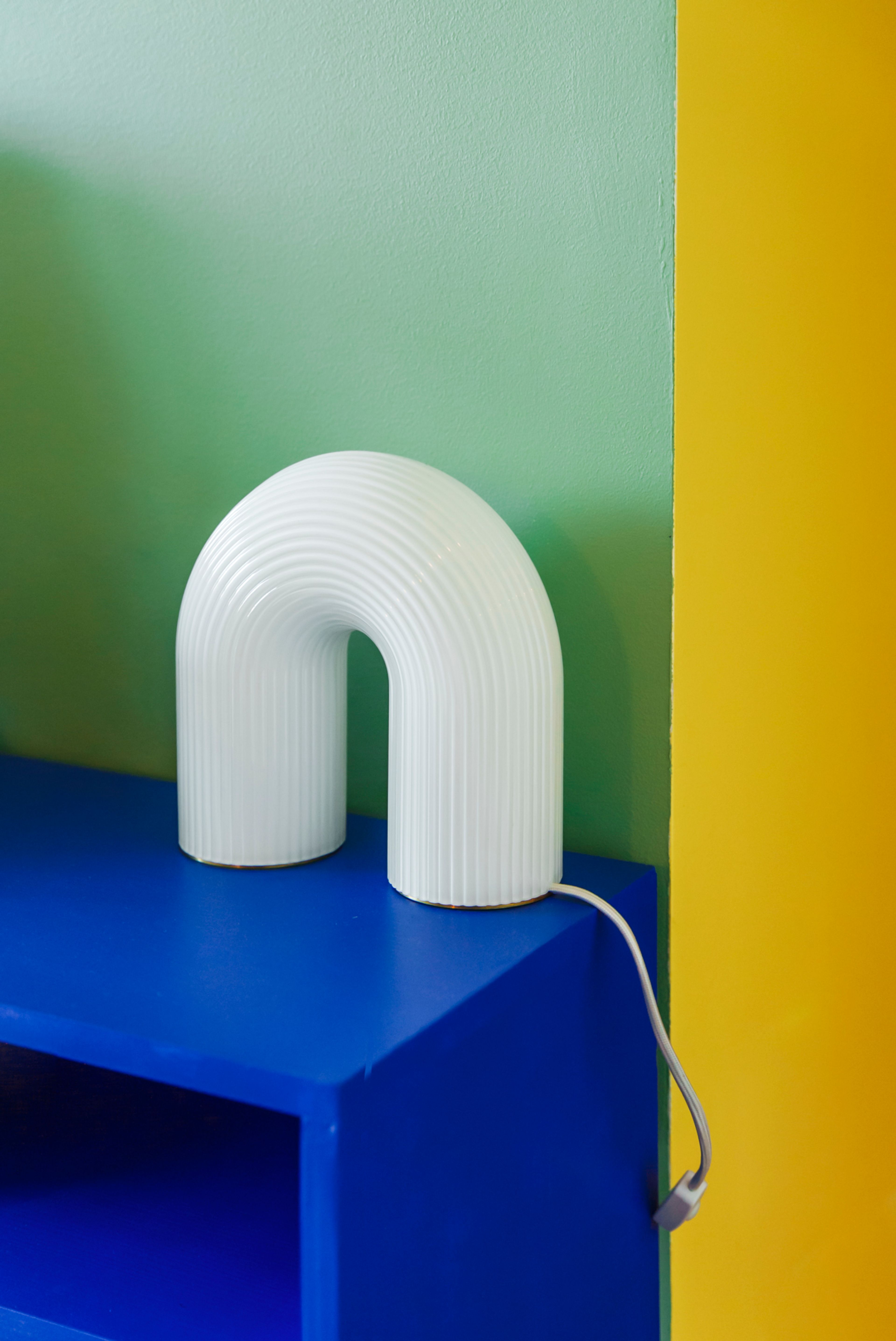 Detalj fra stuen til Ane Engelstad med blå benk, hvit lampe og gul vegg.