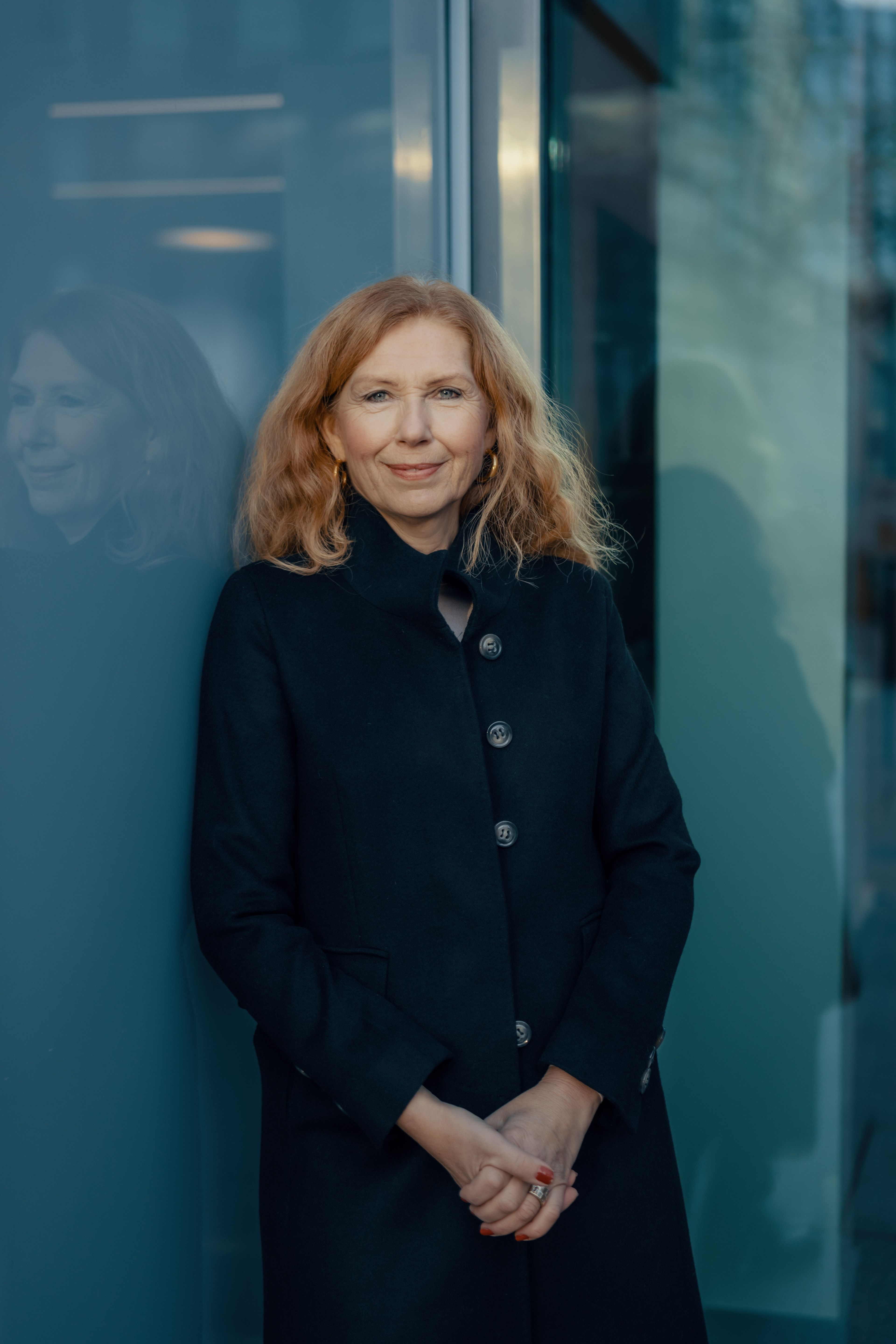 Sissel Monsviold står foran en glassvegg