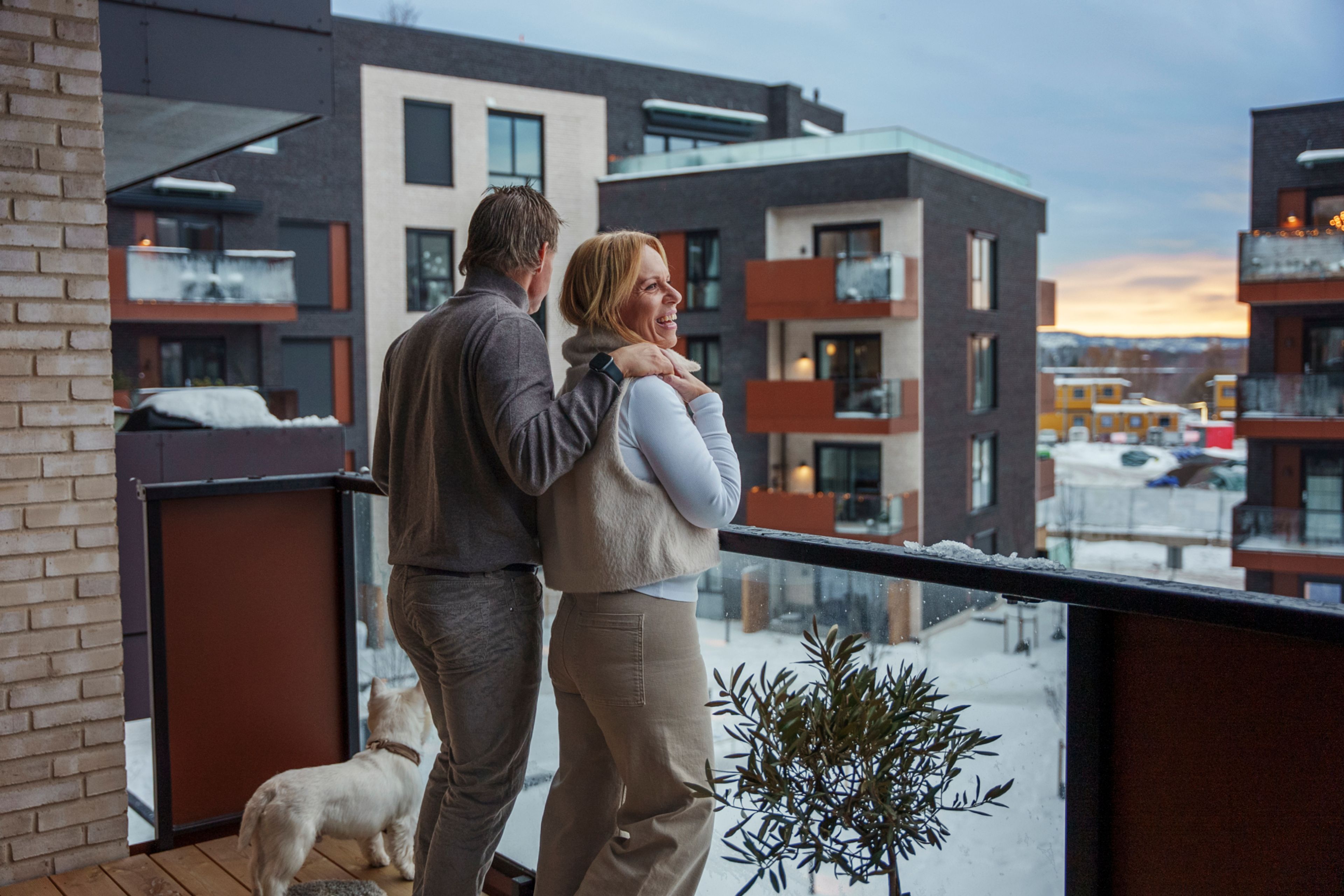 Bilde av Ann-Christin, Frank og hunden Calvin som står sammen ute på en balkong med utsikt mot en snødekt bakgård