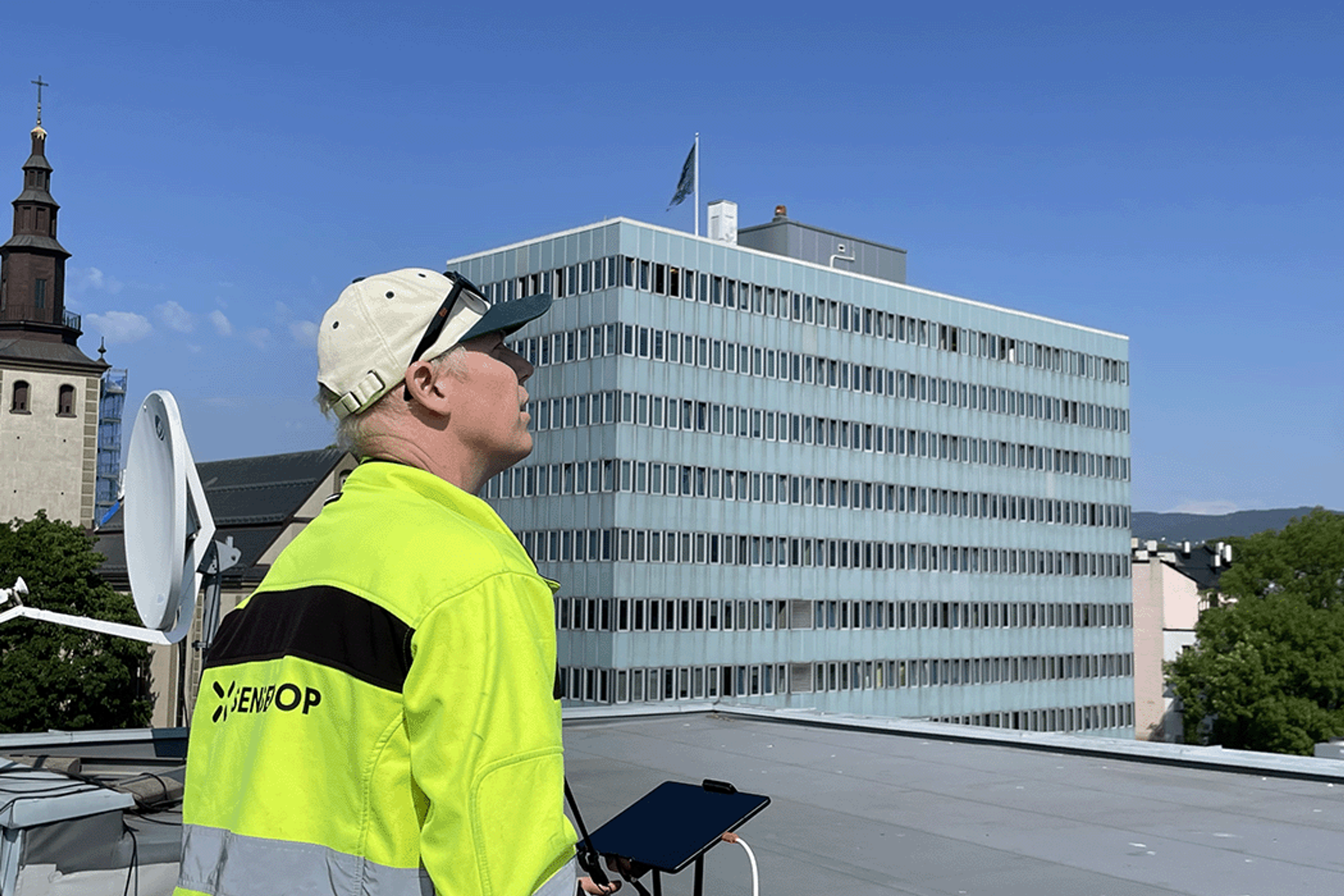 En droneoperatør står på taket til en av nabobygningene til Hammersborg Torg og scanner bygget med drone.