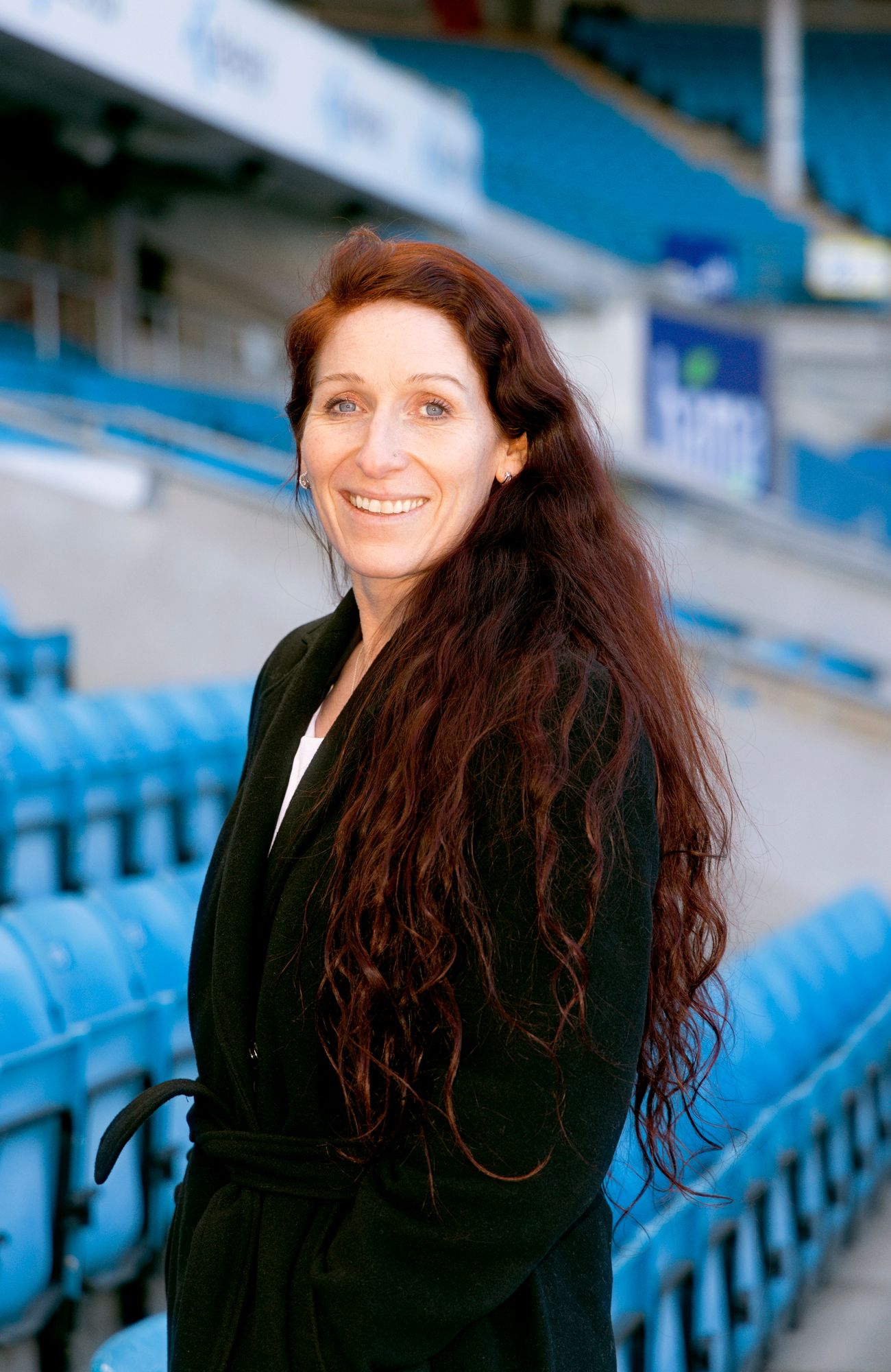 Portrett av Lise Klaveness med blå tribuner i bakgrunnen.