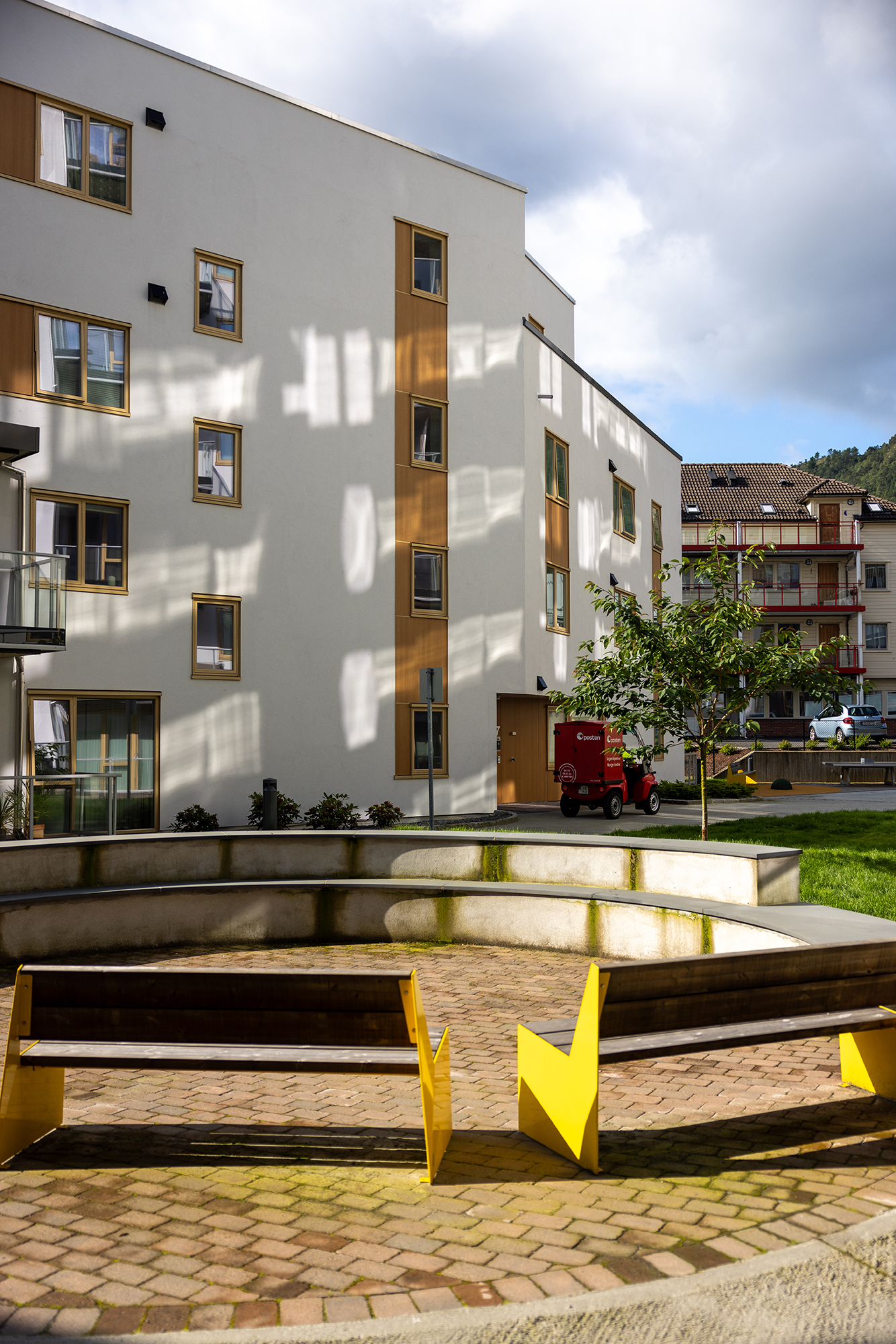 Bilde av to gule benker på en flislagt plass i fellesarealene mellom blokkene i Kronstadparken.