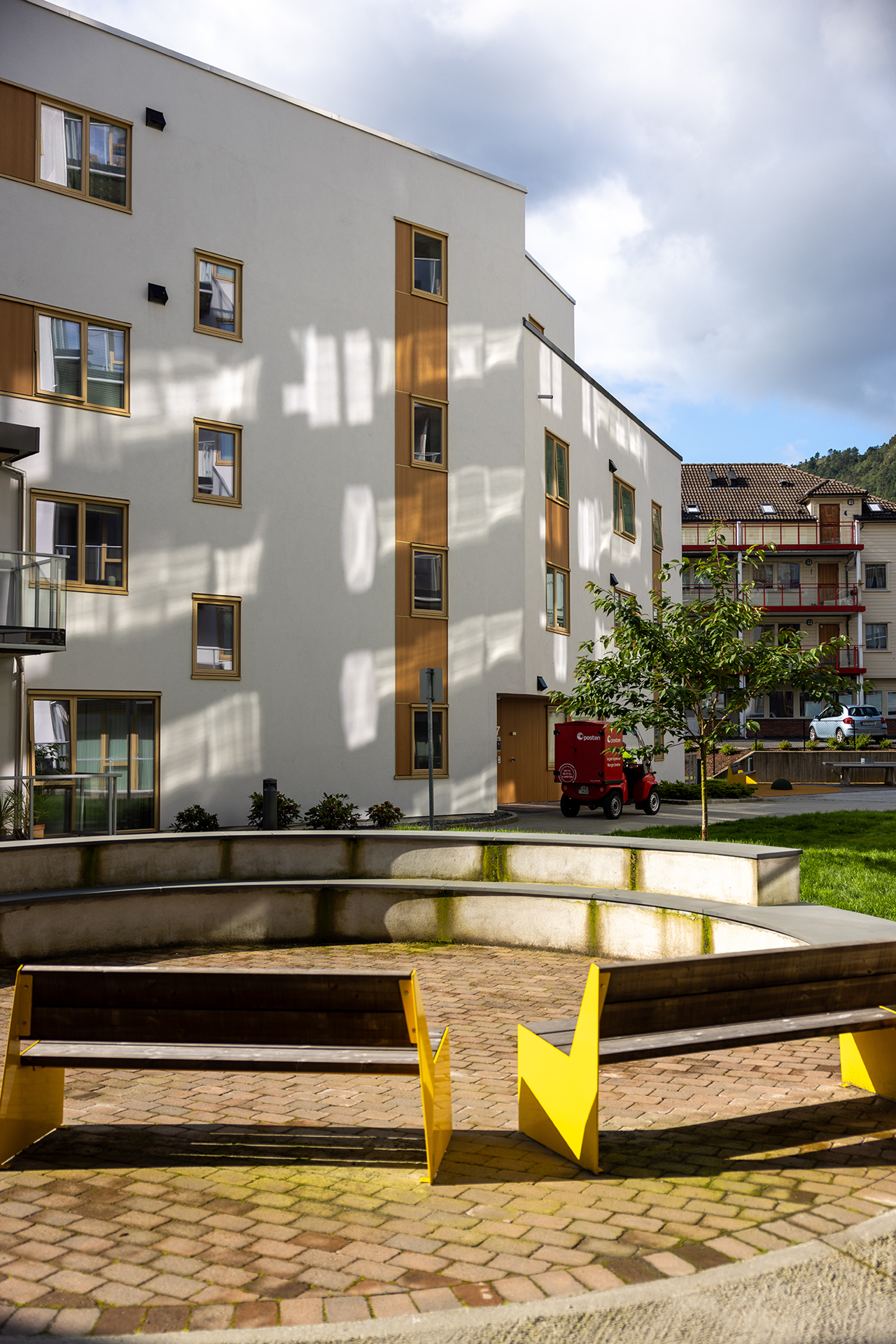 Bilde av to gule benker på en flislagt plass i fellesarealene mellom blokkene i Kronstadparken.