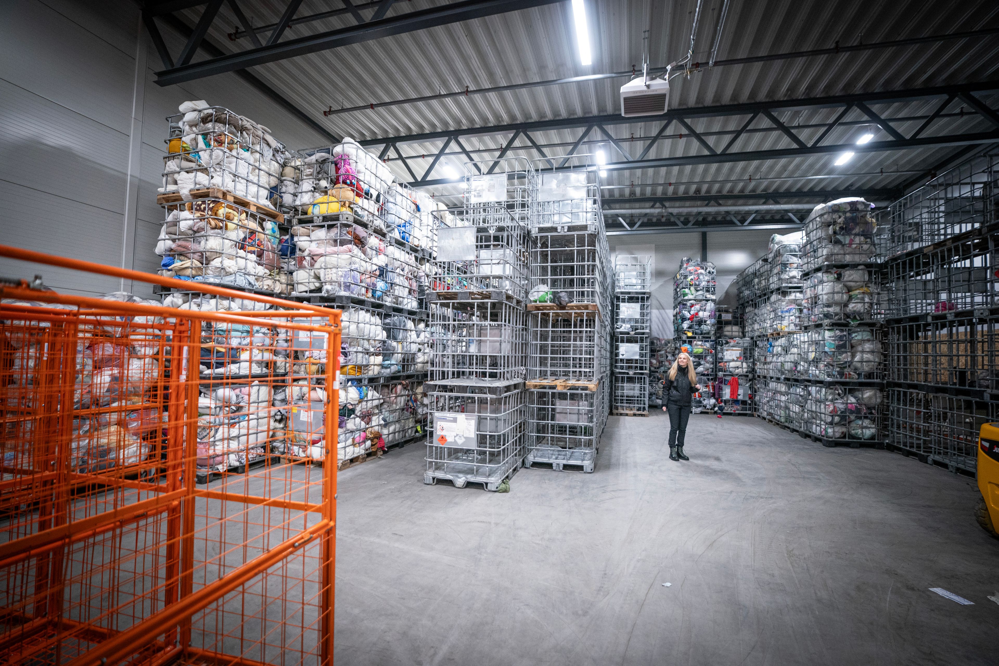 Lagerhall hos Kirkens Bymisjon med stablede metallbur fylt med brukte klær.