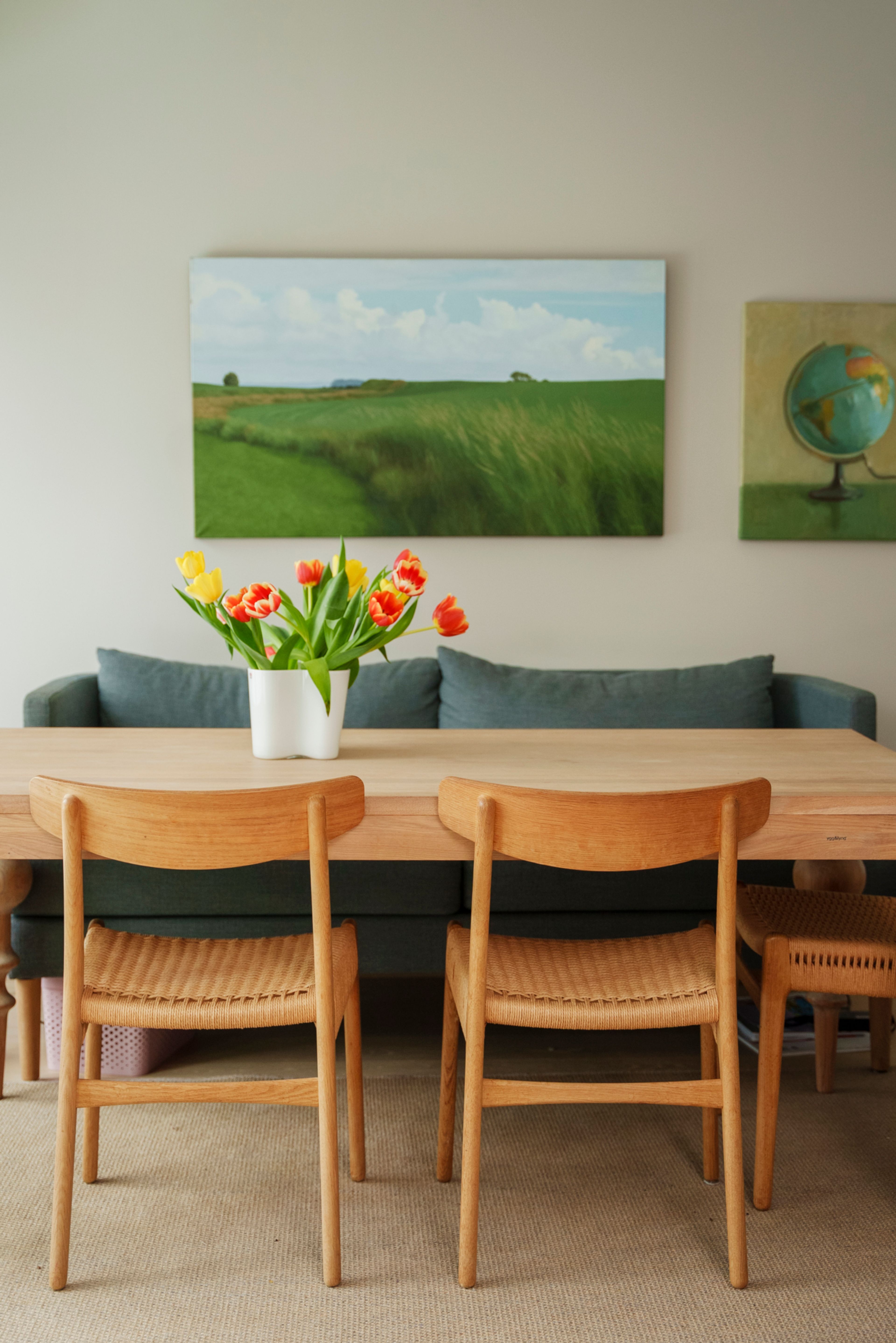 Et bilde av spisebordet i leiligheten på Vitigrend. På veggen henger det to malerier i grønnfarger.