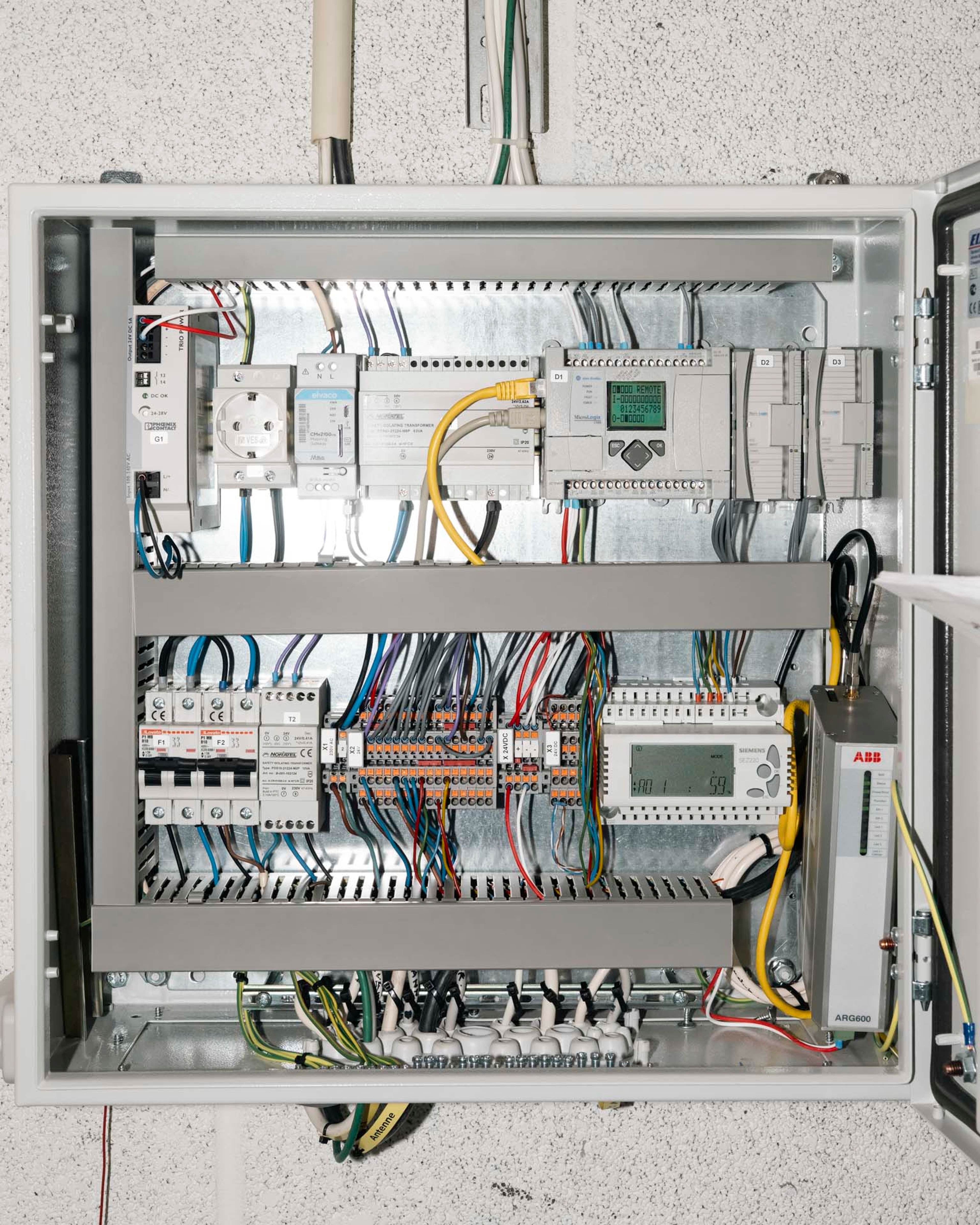 Åpnet sikringsskap som viser ledninger og tastepanel.