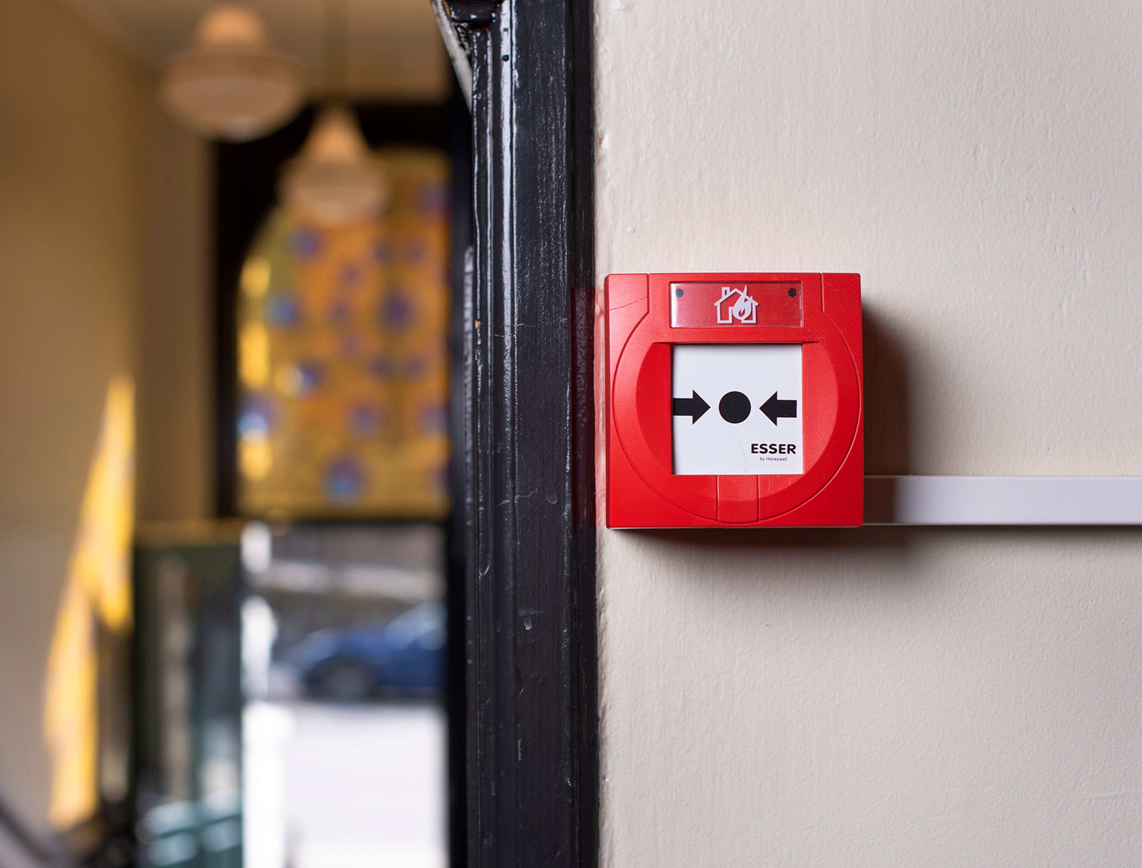 Rød brannmelder montert i fellesområde i en eldre bygård 