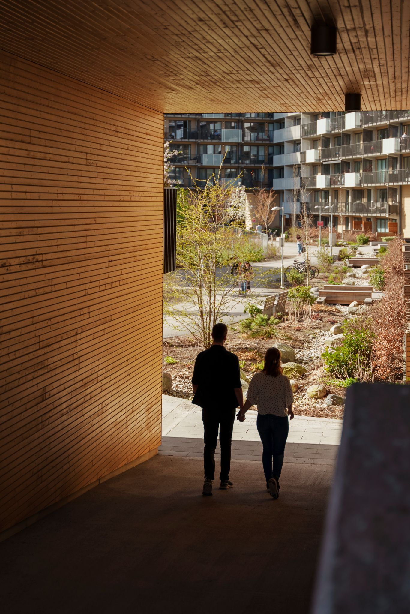 Bilde av et par som går igjennom en mellomgang i et nabolag av leiligheter.