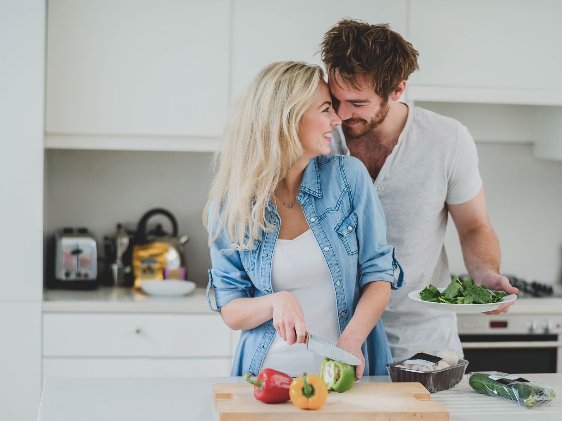 En tjej och en kille lagar mat tillsammans i ett kök samtidigt som de är kära