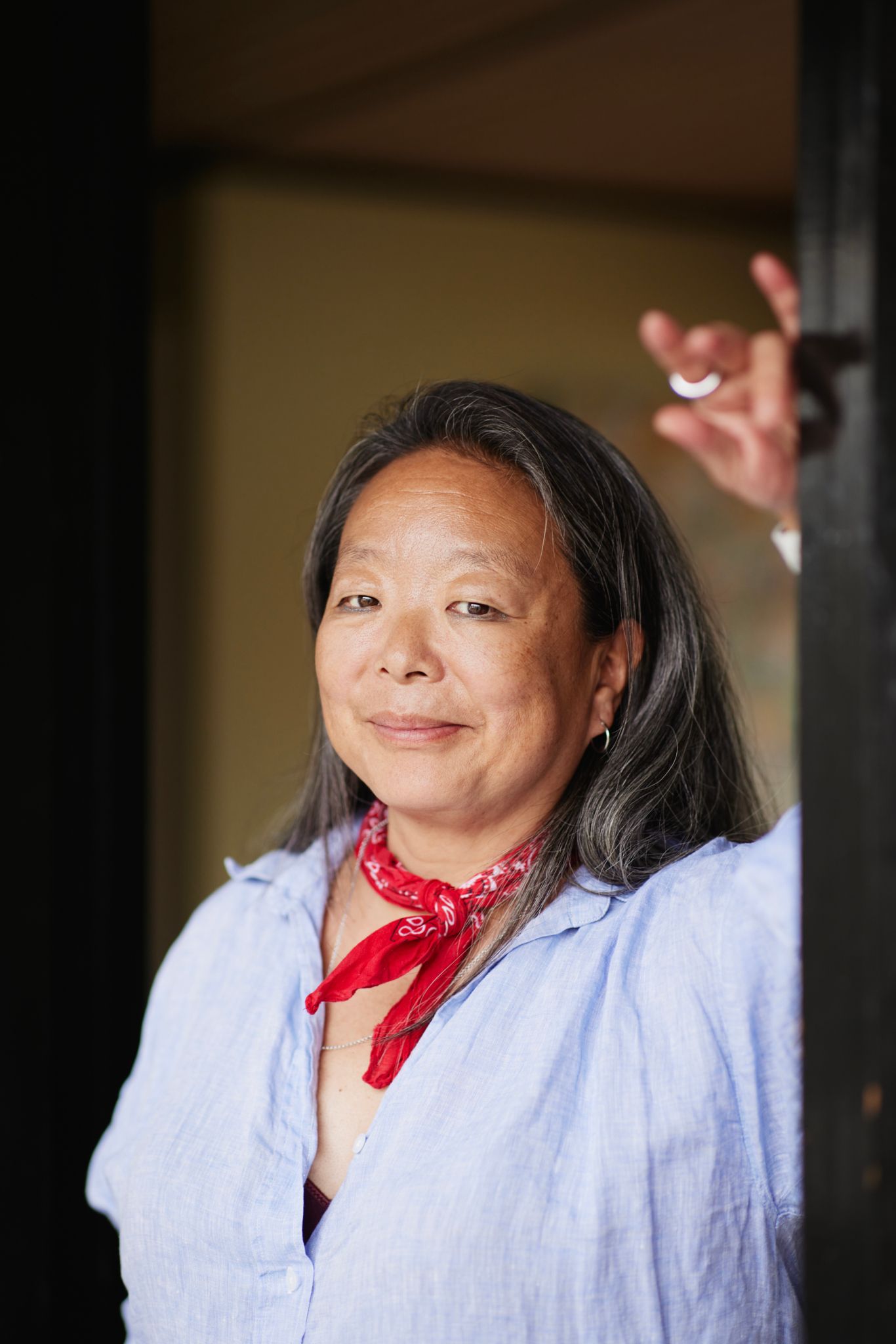 Bilde av en dame som ser i kamera. Hun har et lite rødt skjerf og blå skjorte.