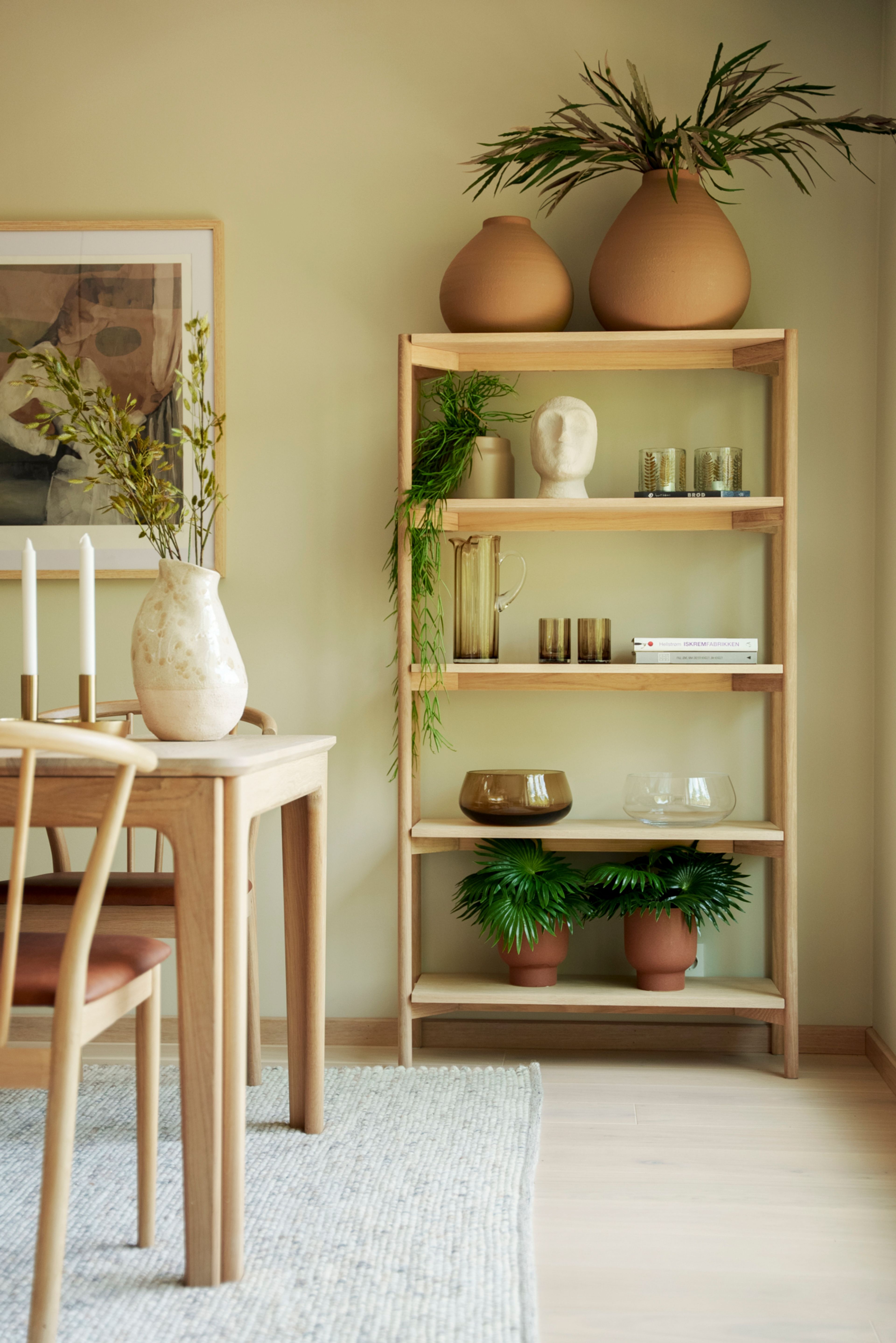 Beigemalt møblert spisestue med spisebord og reol i lys eik