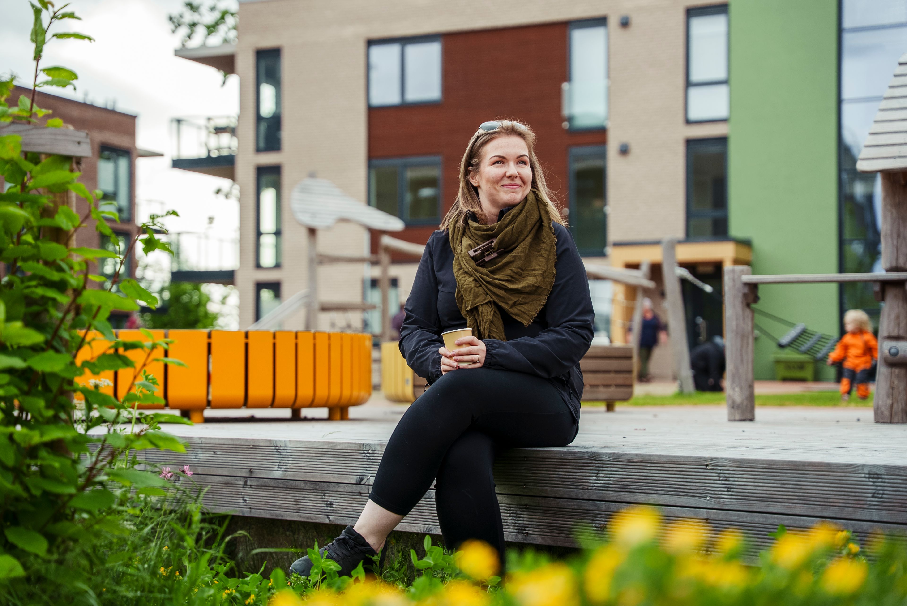 Melinda sitter og nyter en kaffe mens hun smiler