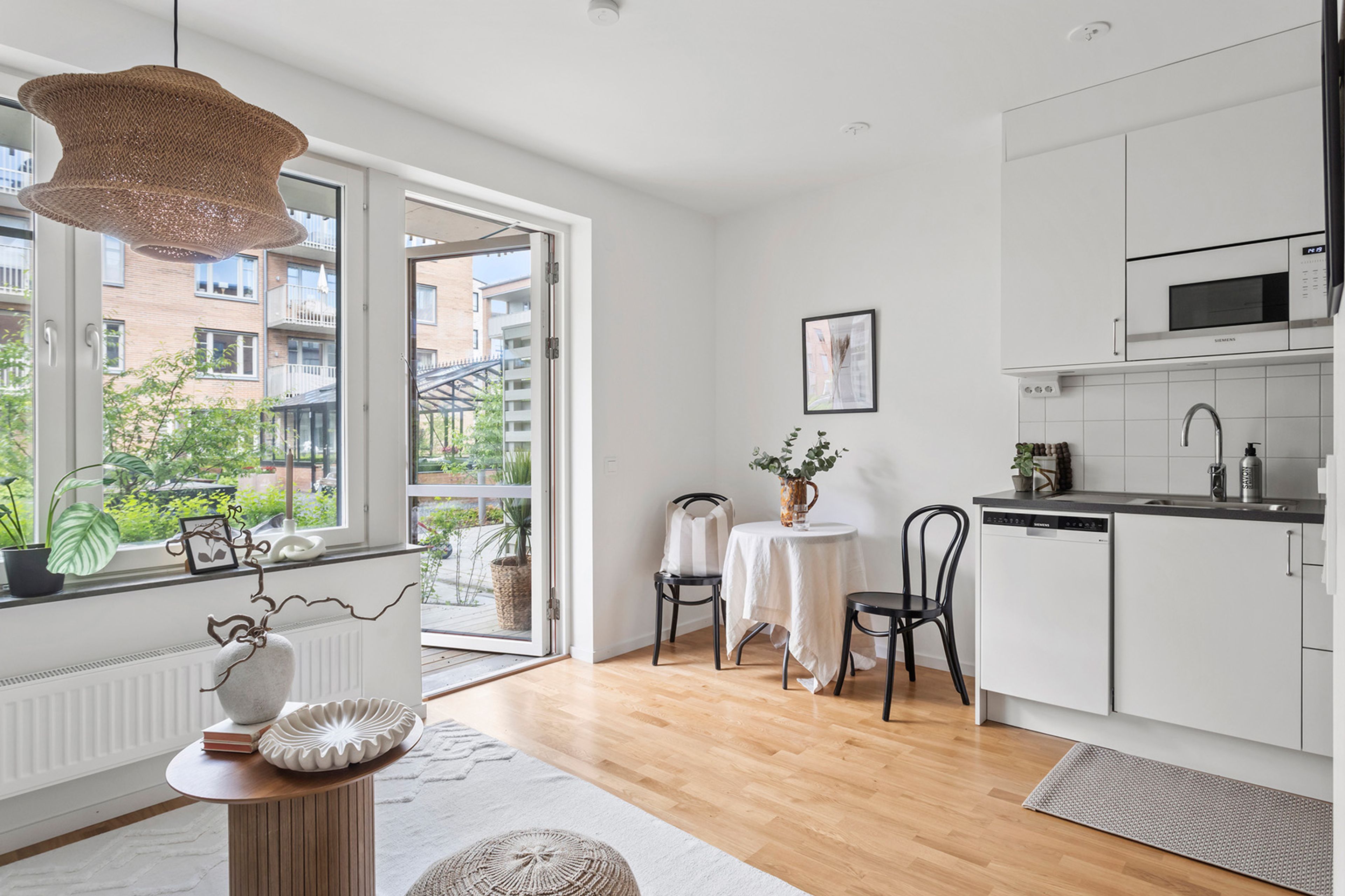 Foto på vardagsrum och liten matplats samt en öppen altandörr