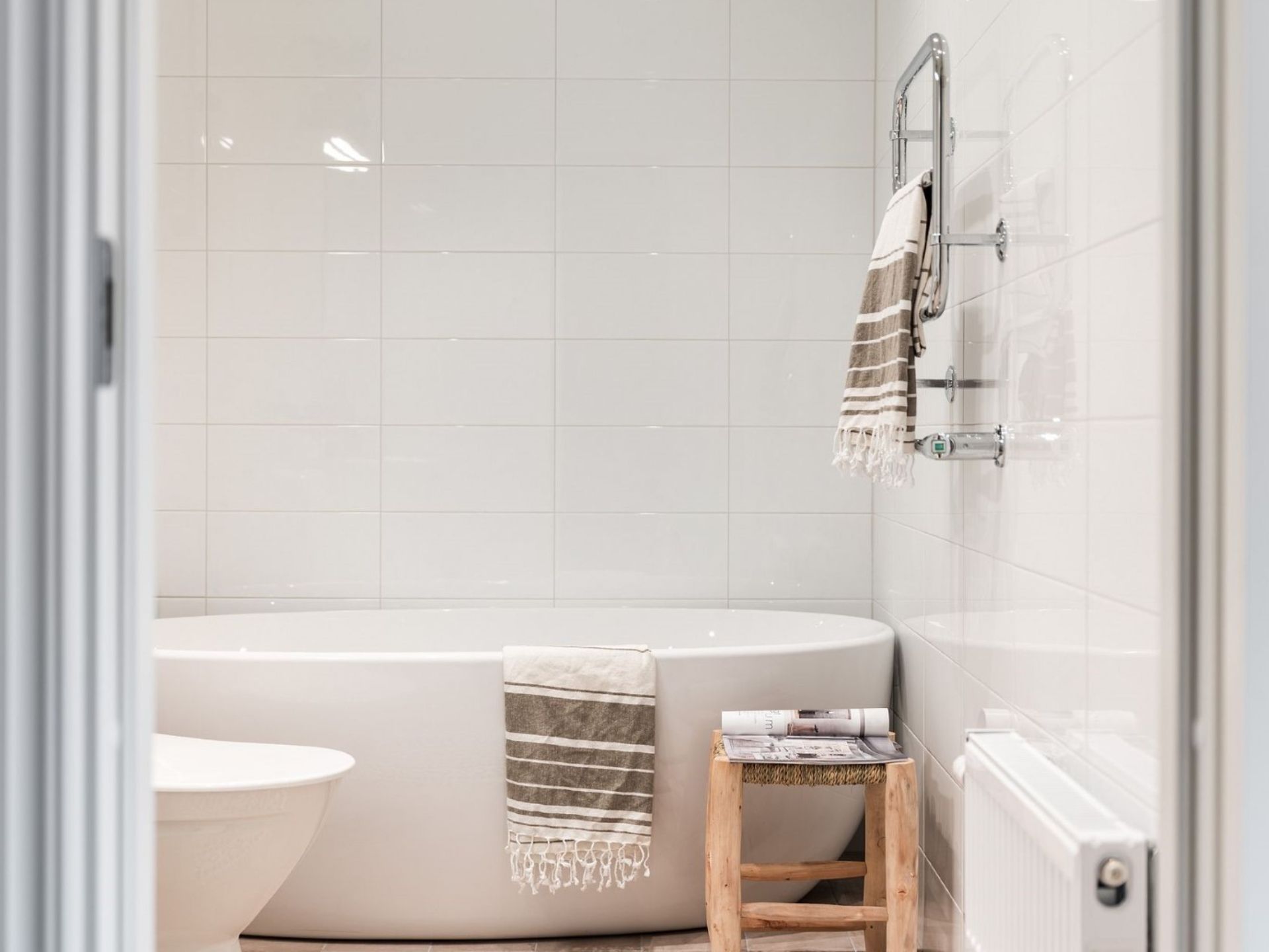 Vitt badrum i vitt kakel med trädetaljer och jordnära färger inspiration