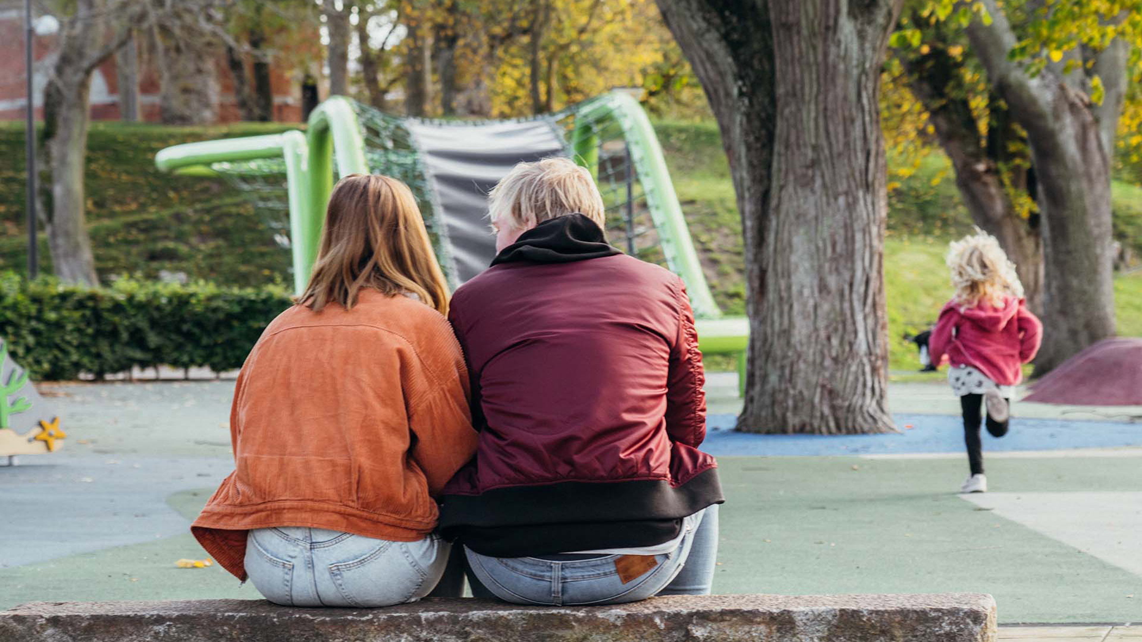 Mamma, pappa och barn i lekpark