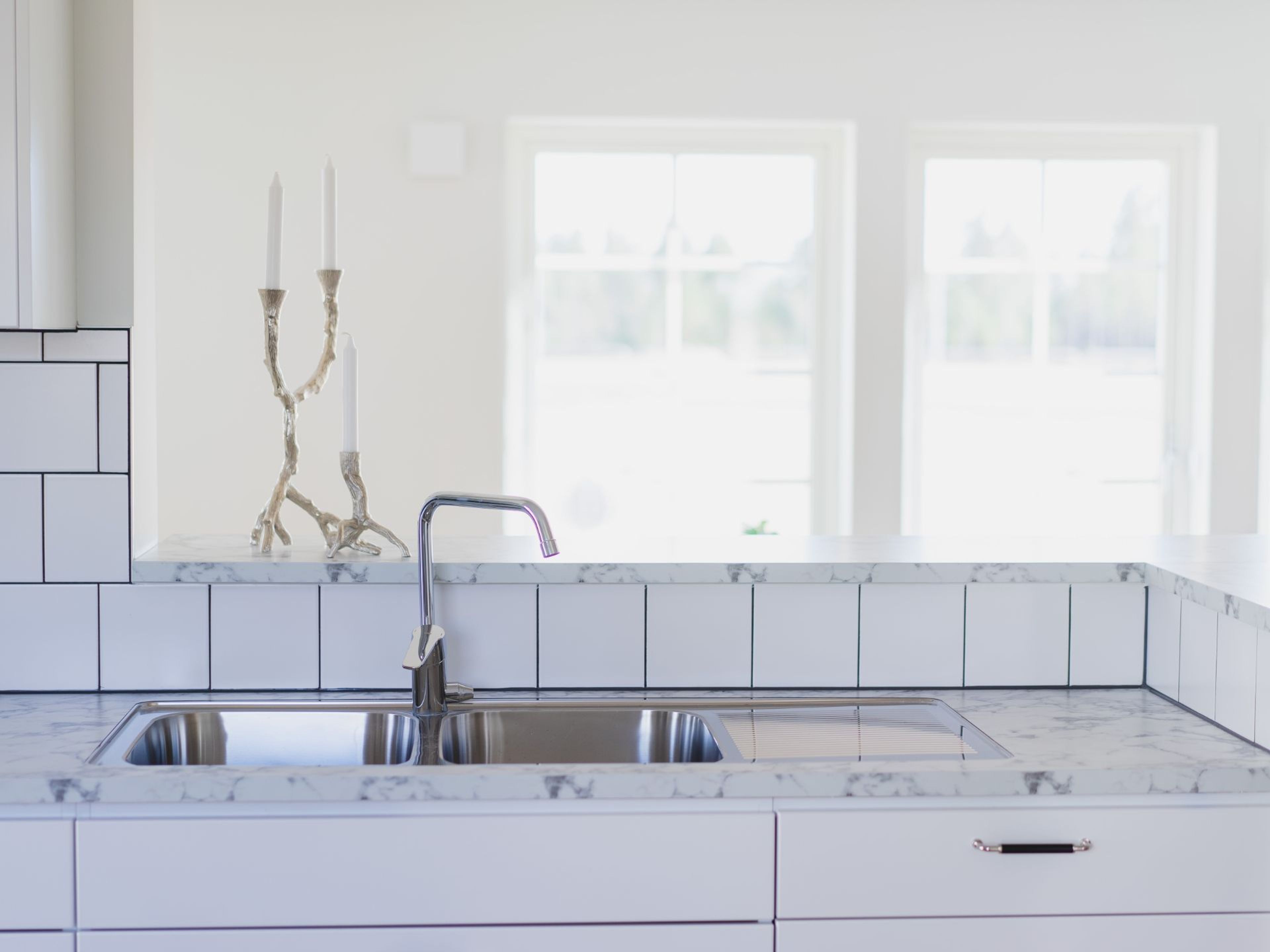 Ljust och modernt k&ouml;k med en diskho i chrom med en ljus marmorskiva