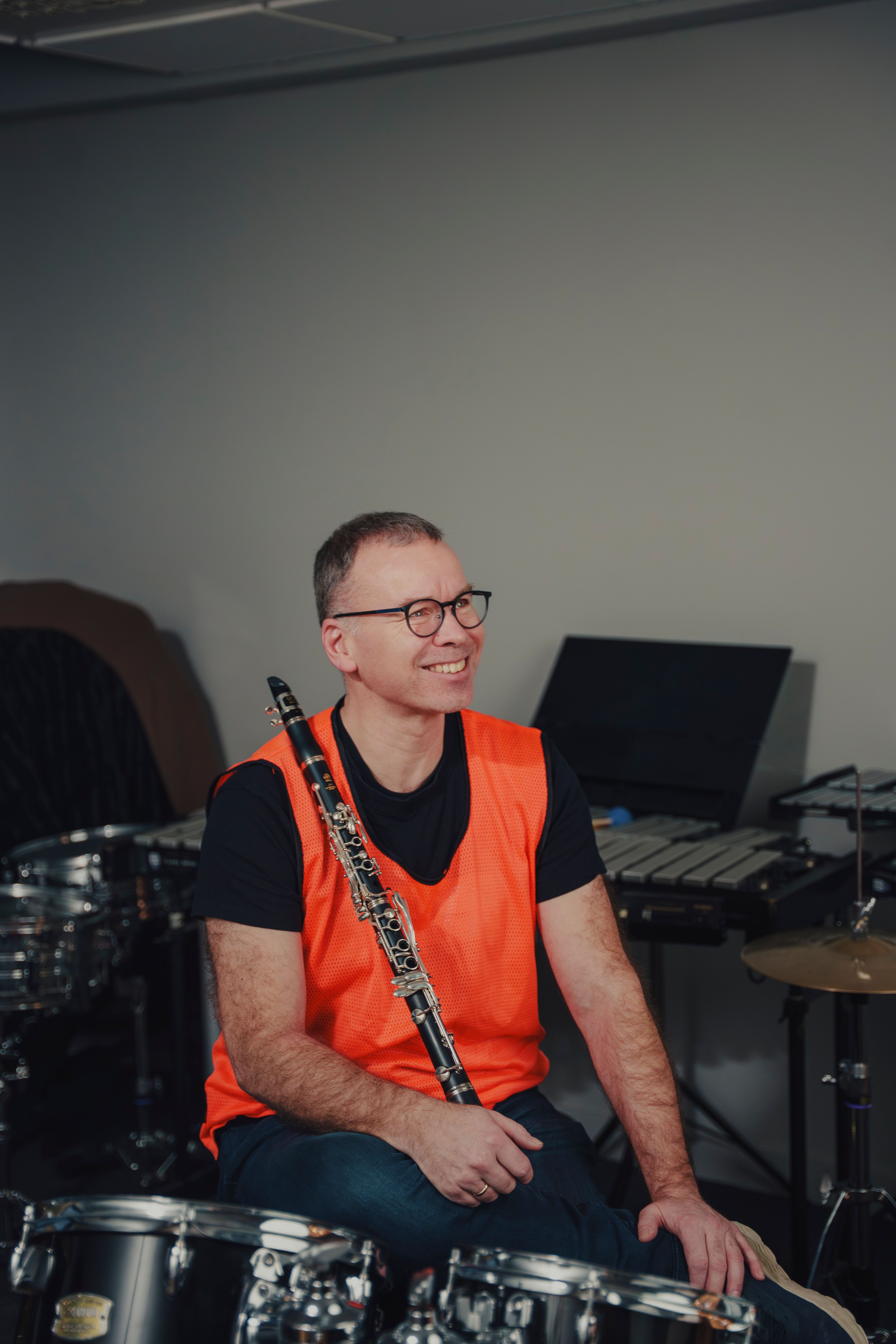 Per Christian Kittilsen smiler bredt mens han holder klarinetten foran seg, med trommer og marimba rundt seg.