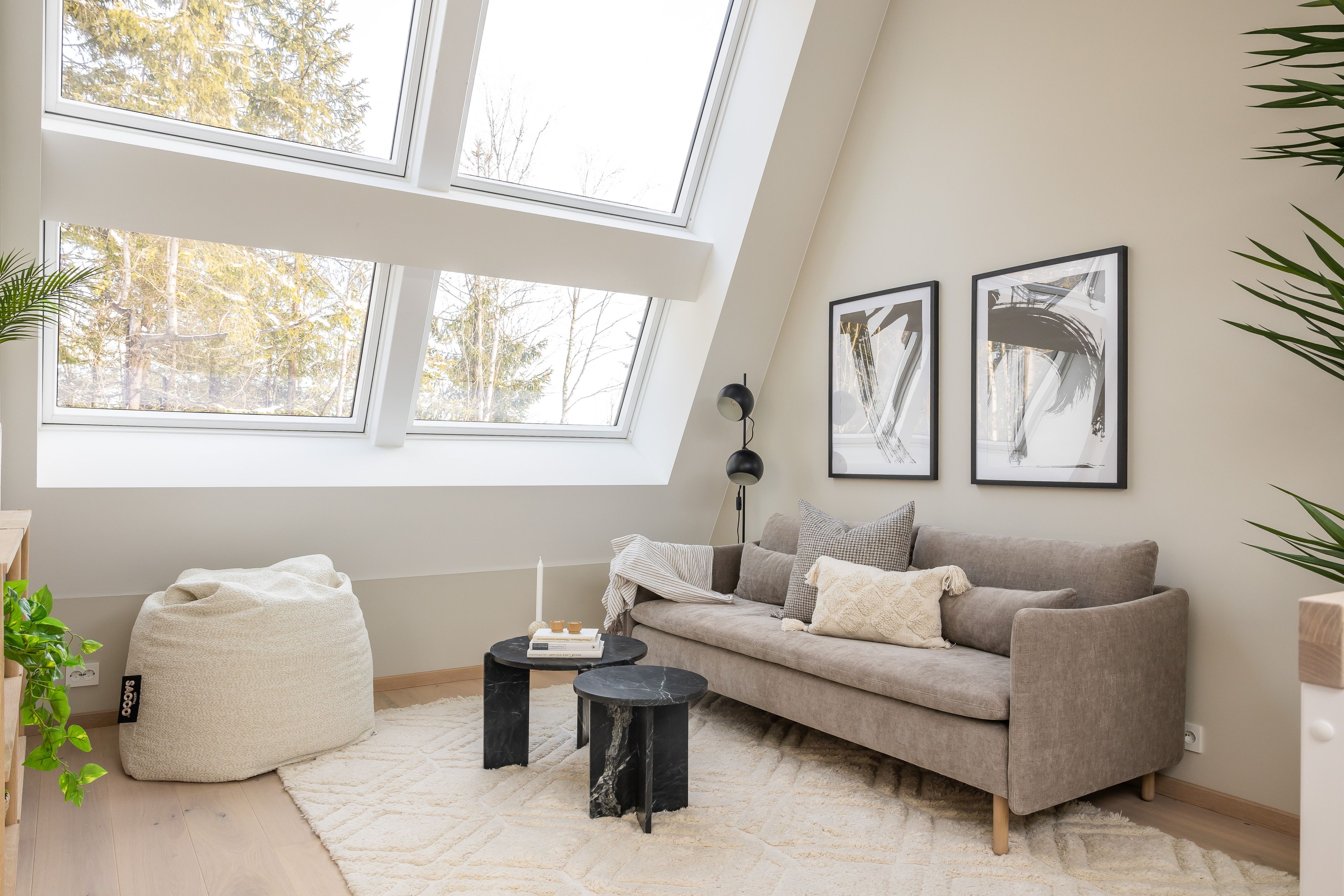 Foto av liten stue med sofa, sofabord og store vinduer.
