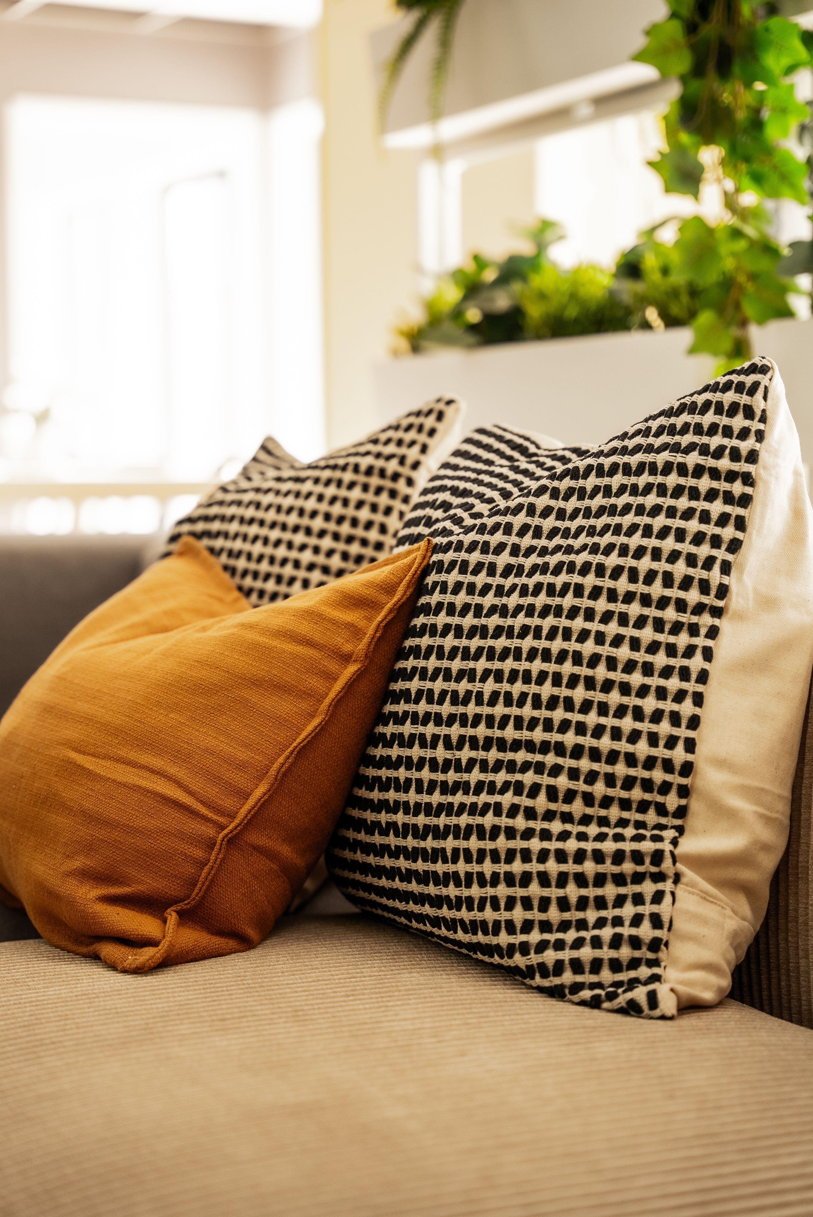 Nærbilde av puter i en sofa, i grå- og bruntoner.