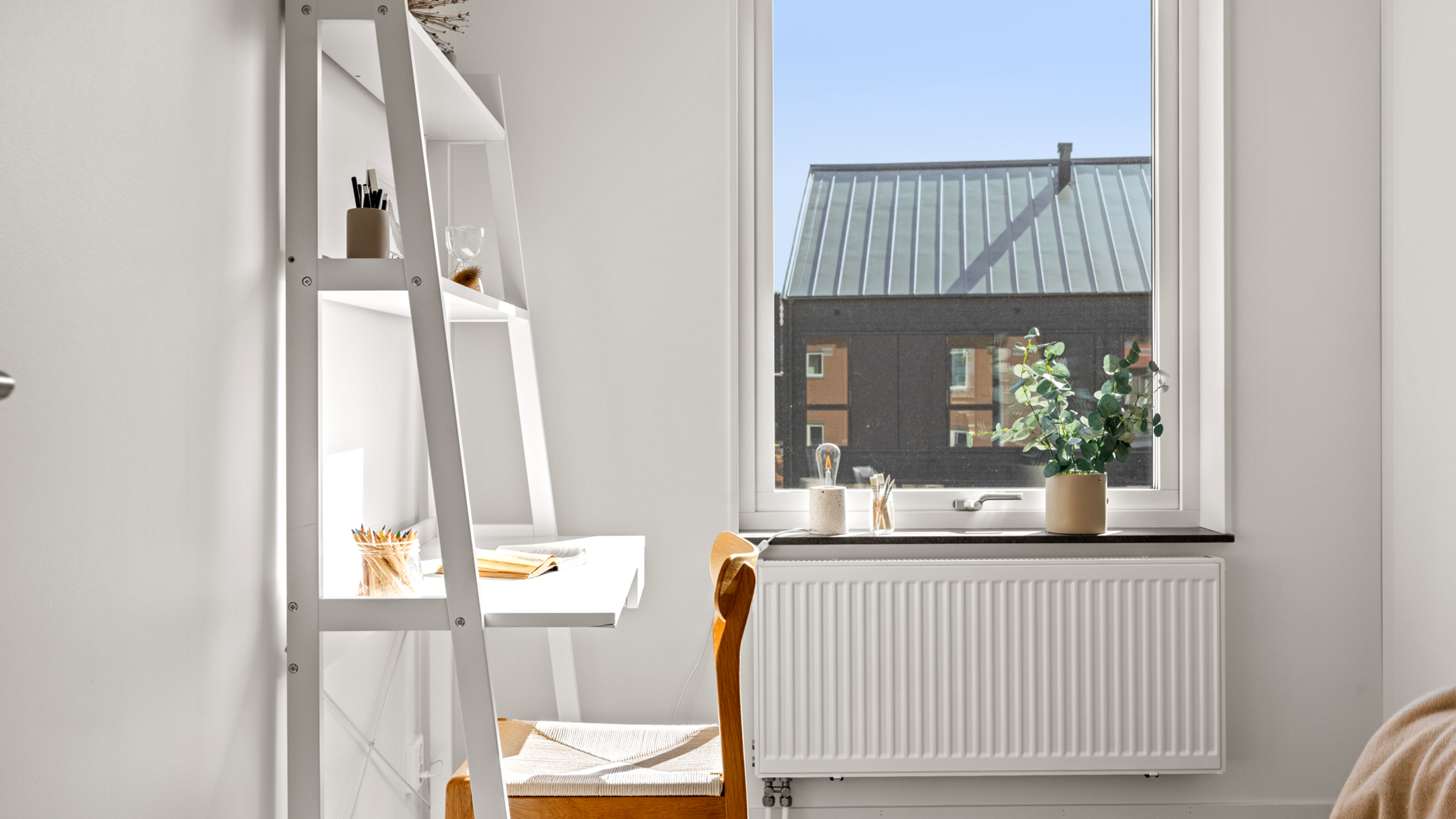 Gästrum eller kontor med skrivbord och stol intill fönster med utsikt mo mörka hur mitt emot
