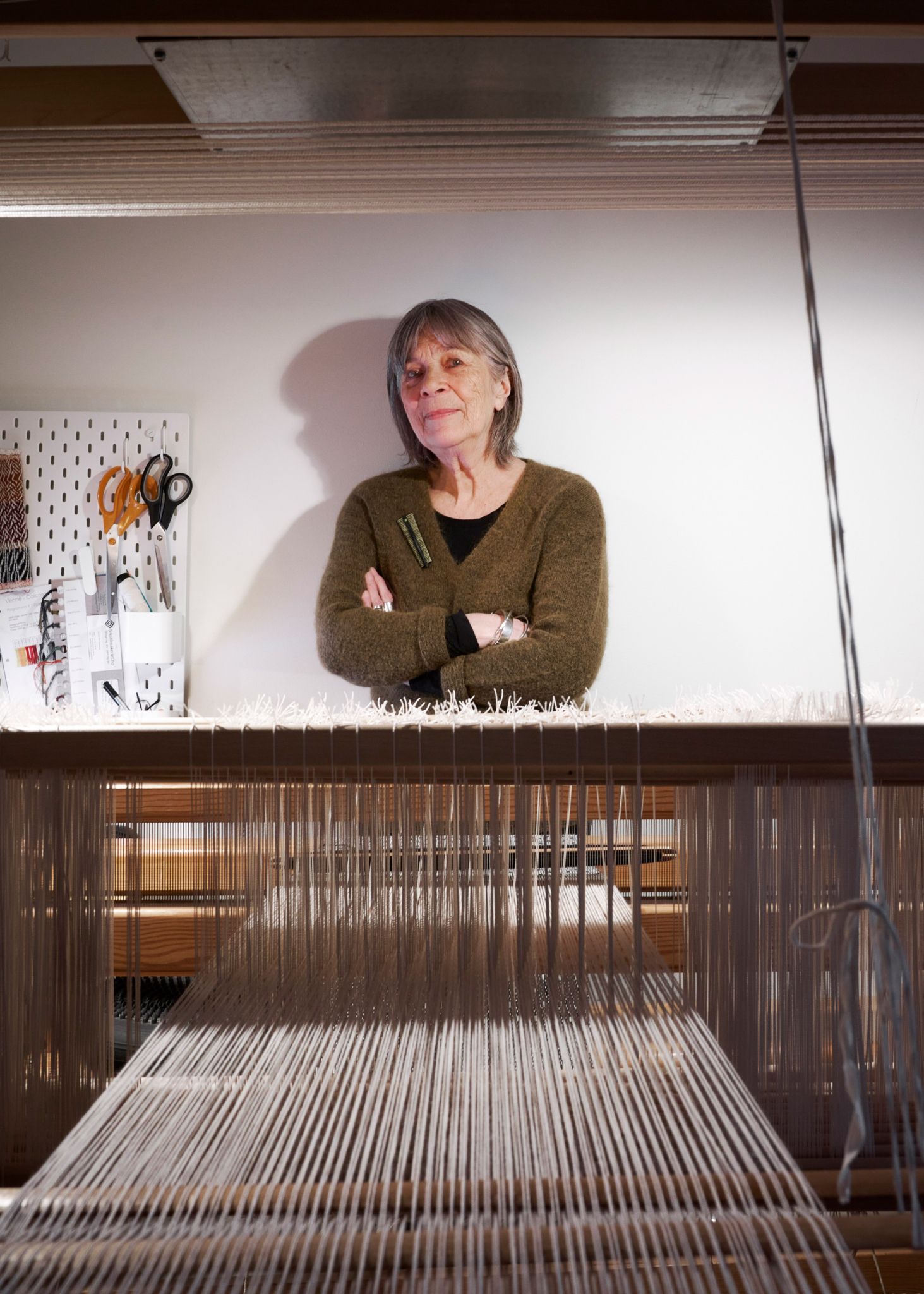 Foto av Marit bak veven sin på Sandsliåsen.