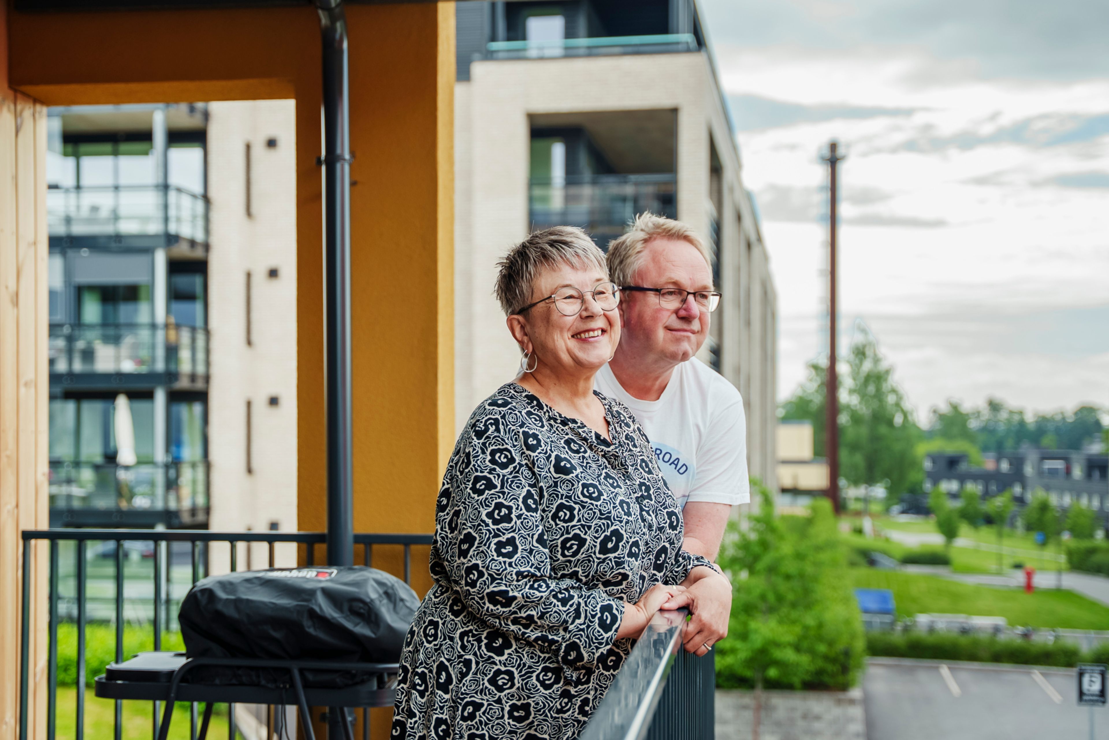 Et par står fornøyde på en balkong