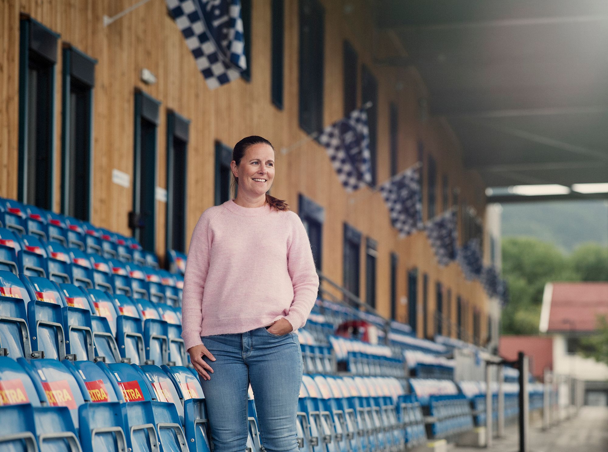 Stina står foran tribunen på Ranheim Stadion, med flagg i bakgrunnen.