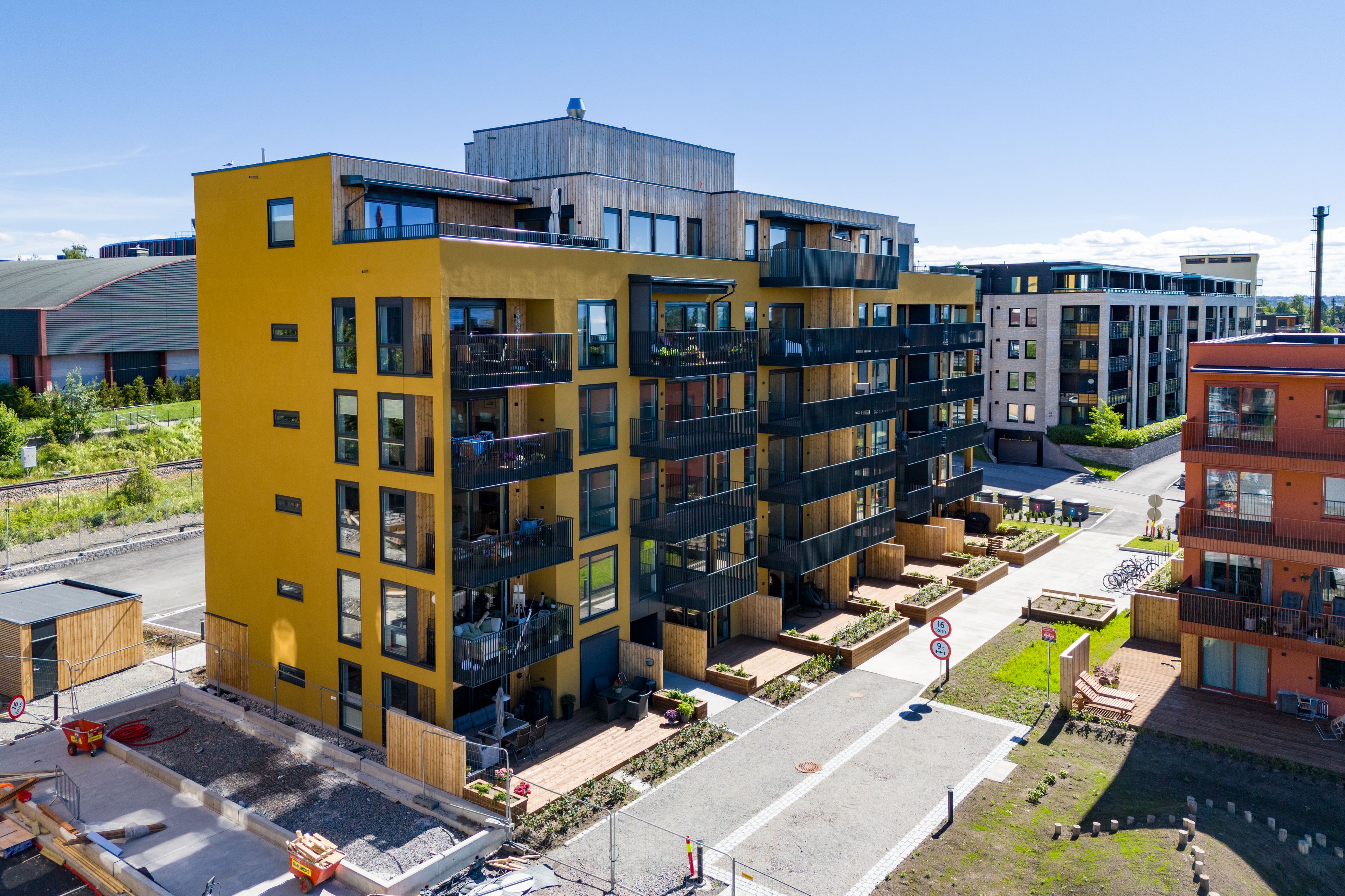 Den gule fasaden til hus B i Stålverket Torg med balkonger og grønt arealer.