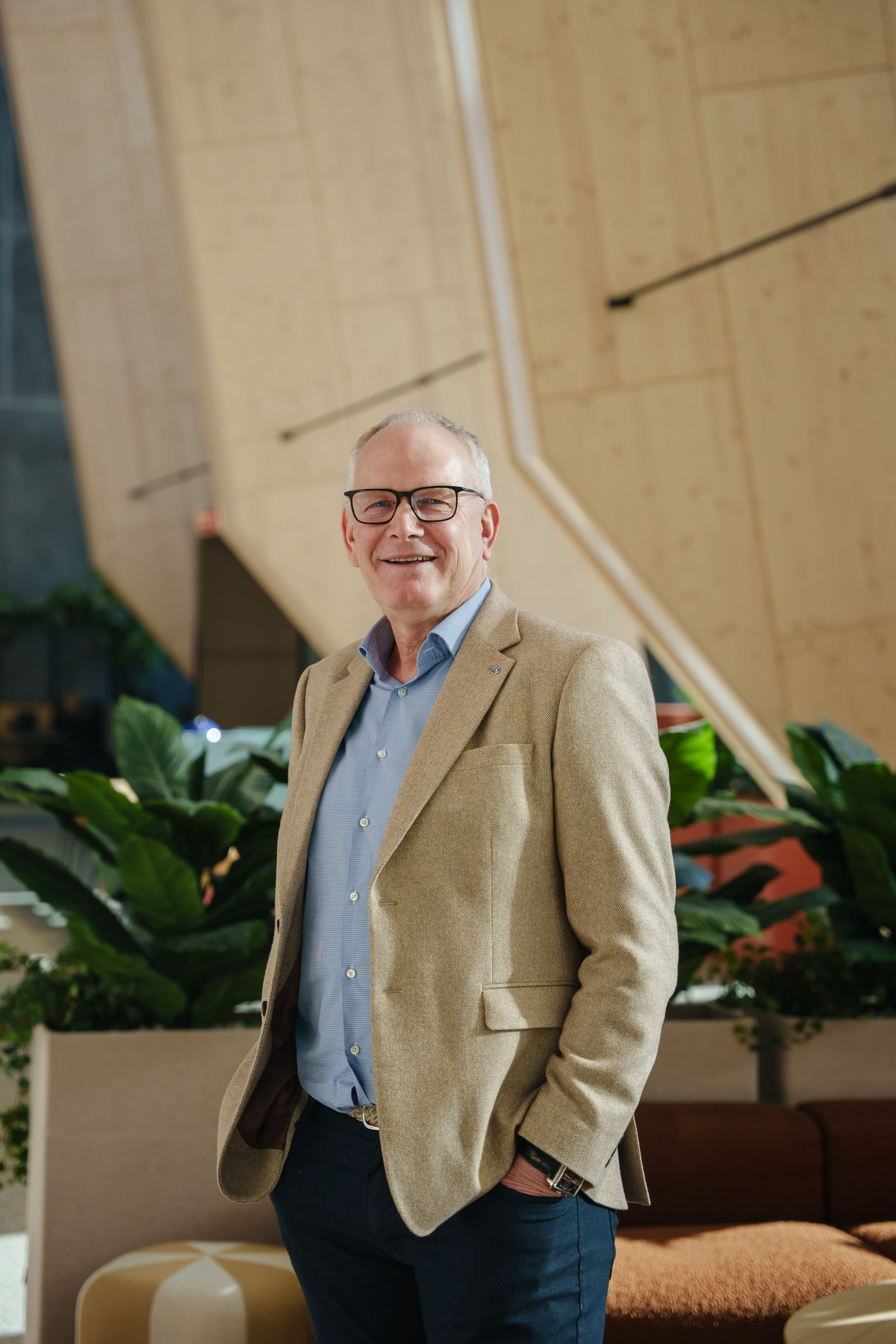 Portrettbilde av Bjørnar Tretterud i et stort, moderne rom med mye treverk.