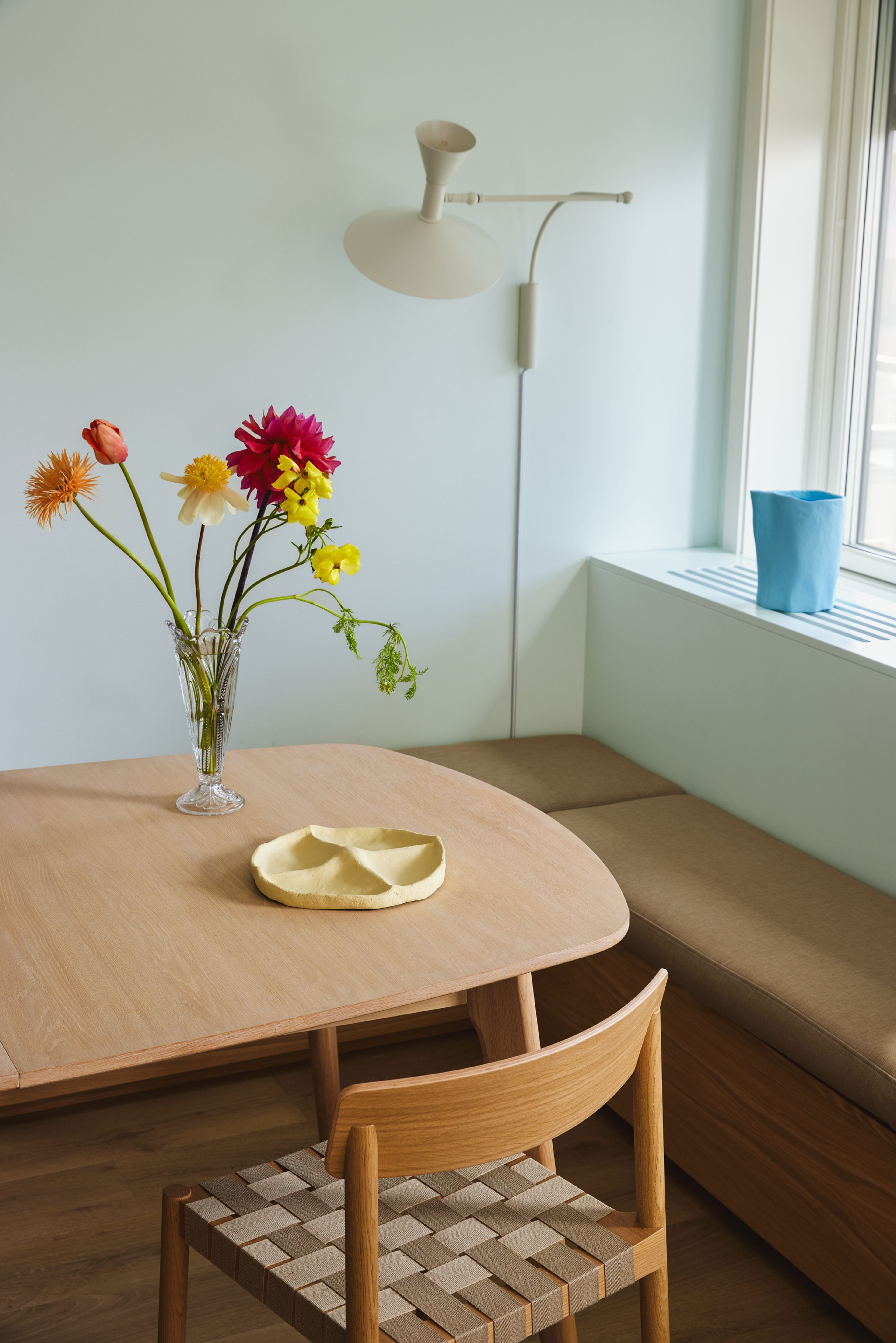 Nærbilde av stuekroken til Eirik og Ida, med et trebord, en stol, en benk og lyse veggfarger