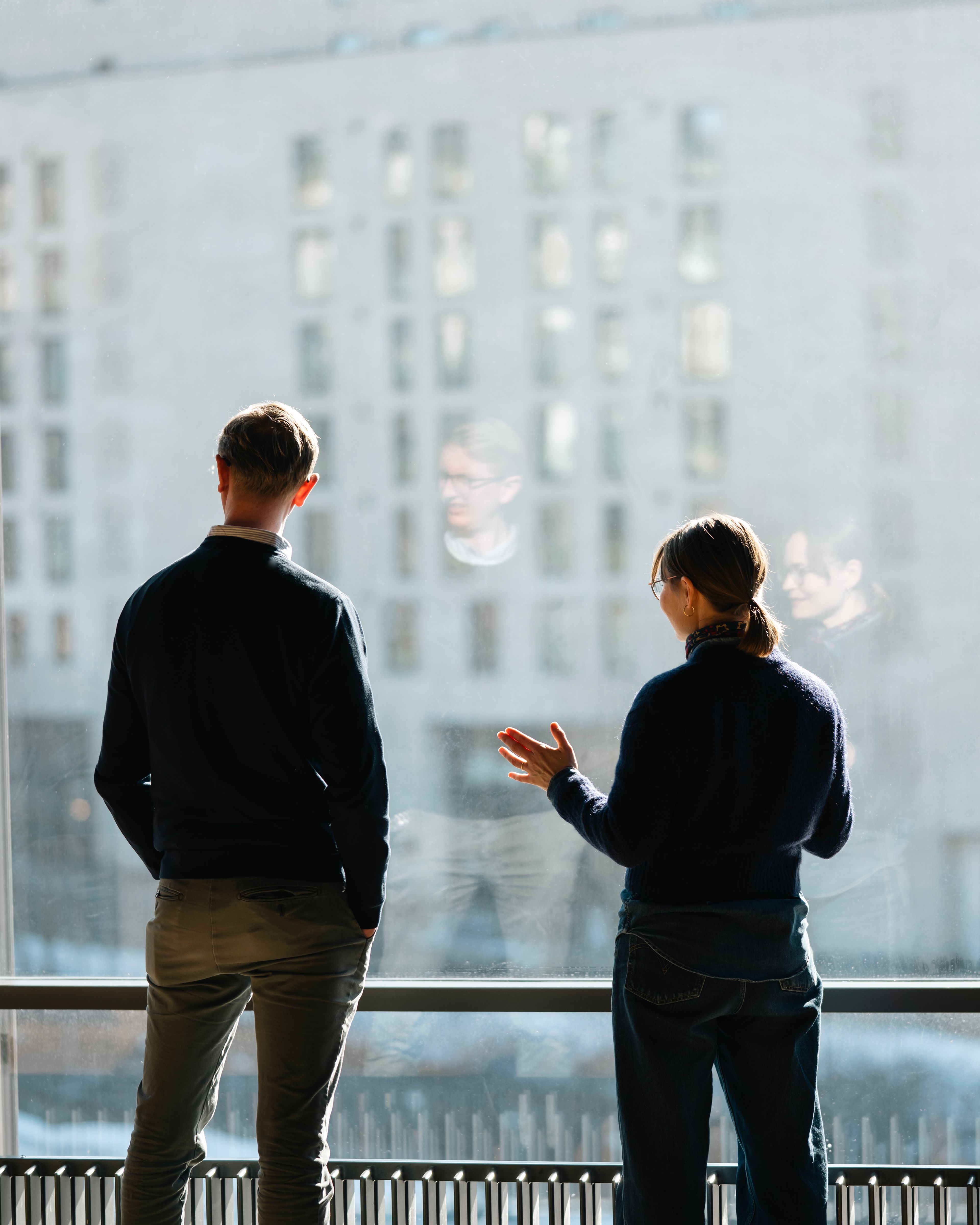 Foto av Peter Pay og Katrine Lone Thomson stående ved et stort vindu, på innsiden av kontorbygget tilhørende Trykkeriet i Nydalen.