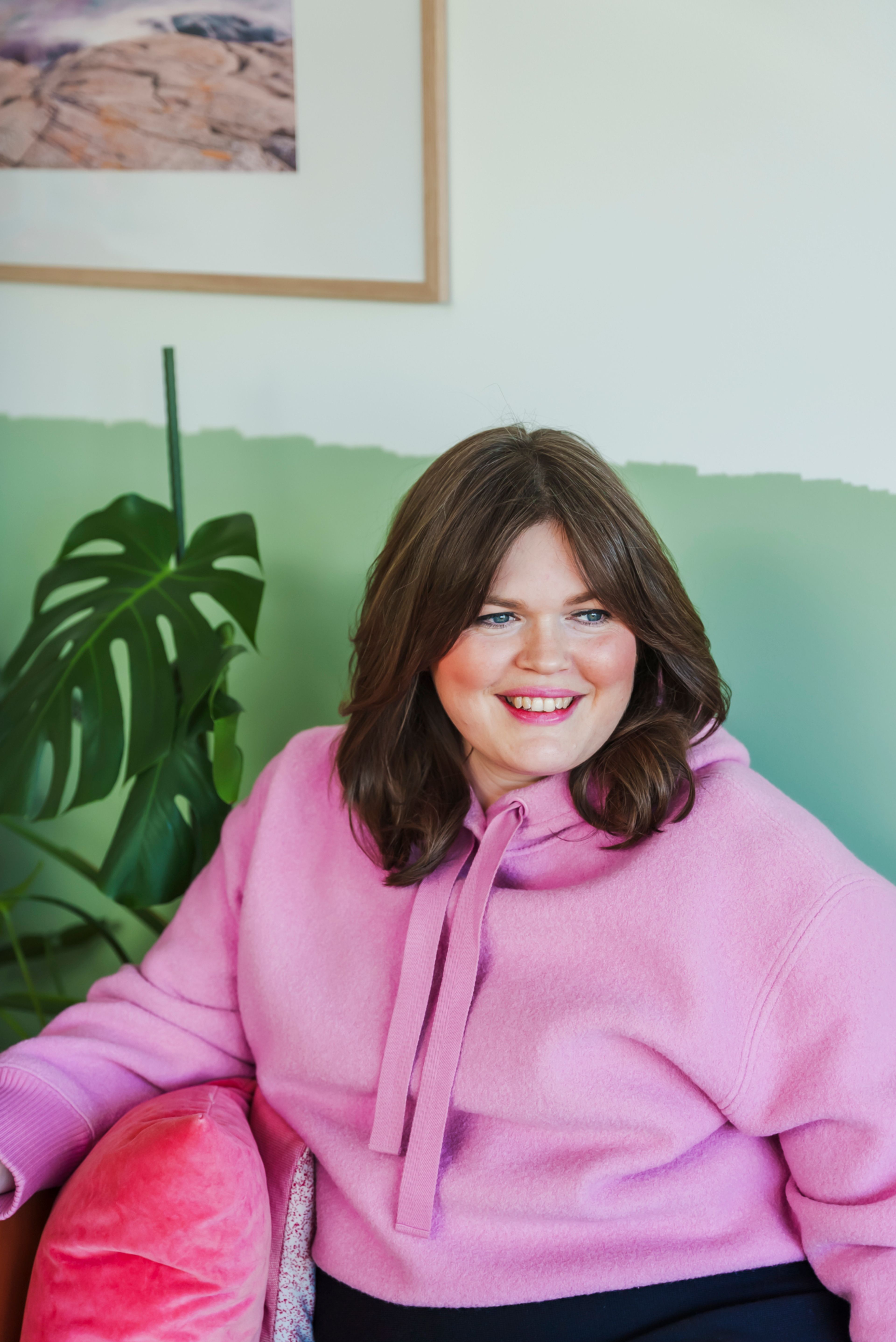 Ane sitter en i en sofa med rosa hettegenser