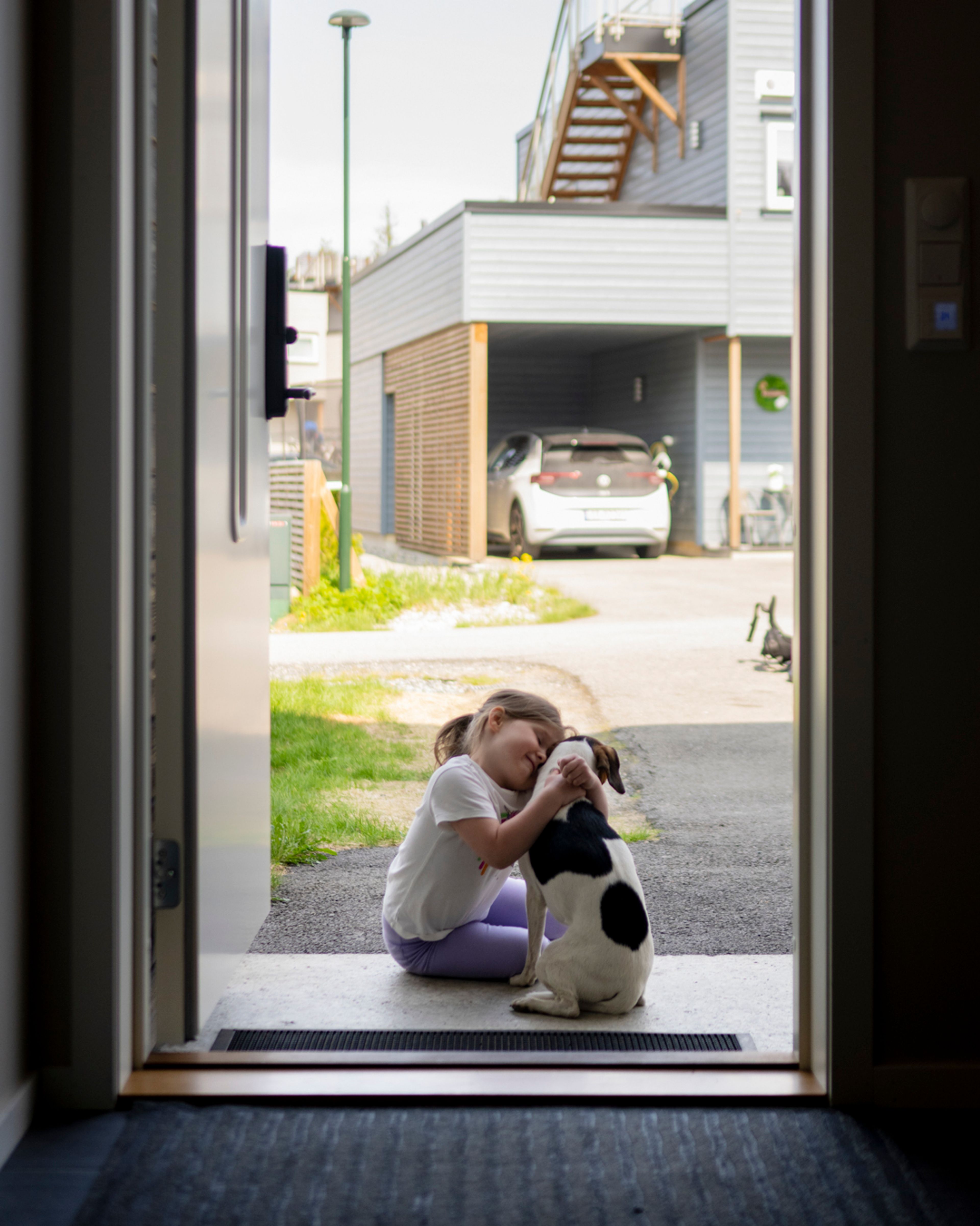 Foto av barn som klemmer en hund i en døråpning.