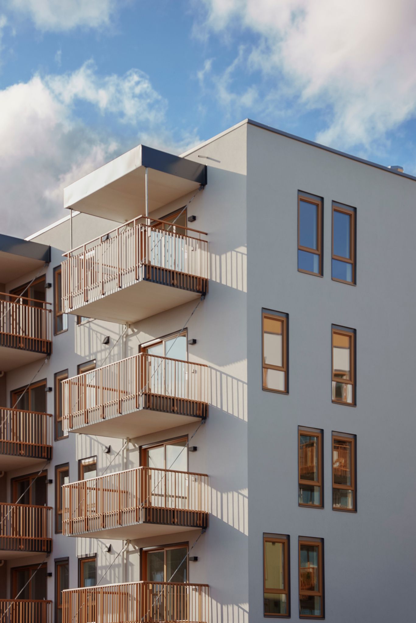 Totalbilde av hjørnet på en av blokkene i Asper Hageby, med hvite vegger og mørke balkonger.