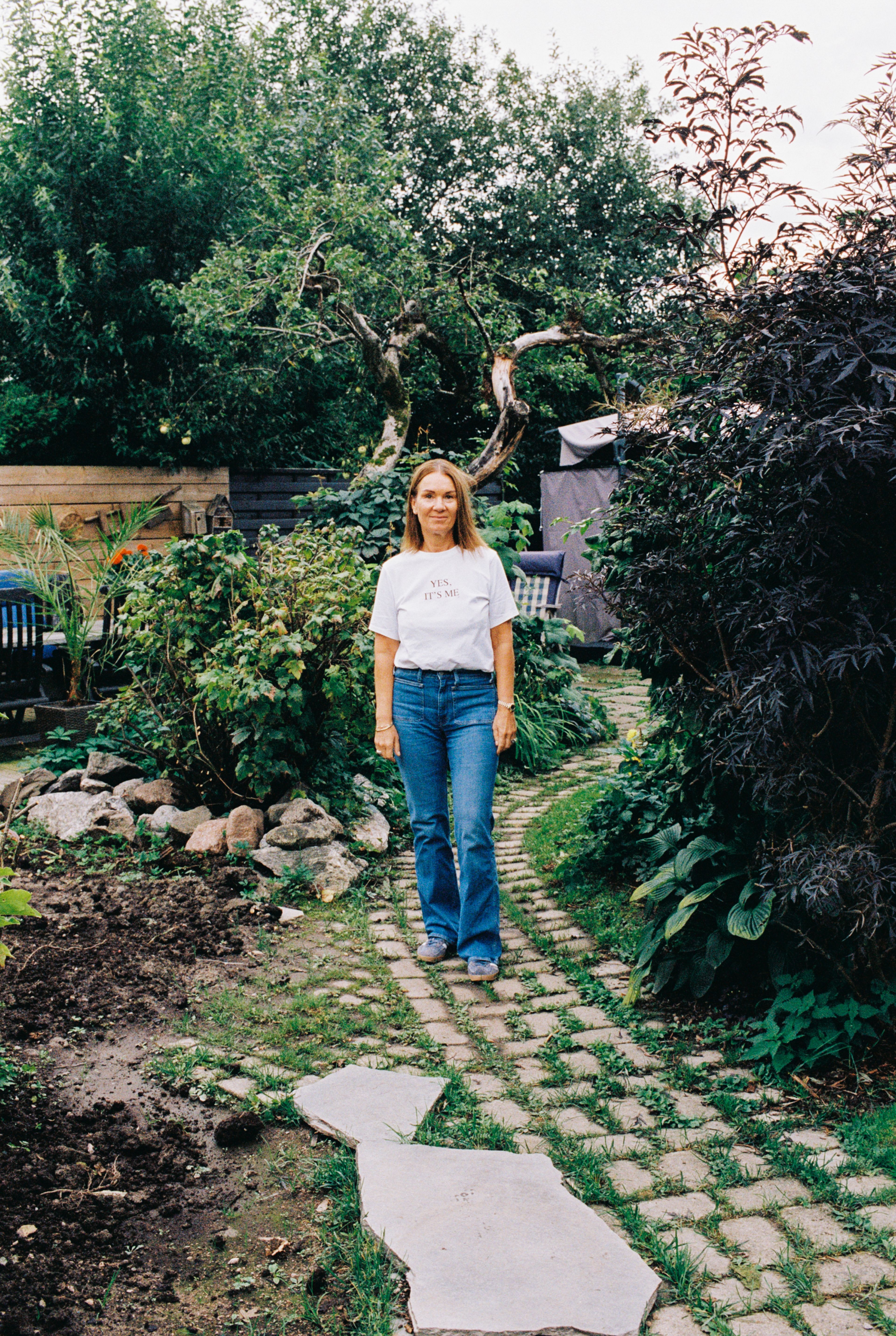 Bilde av Camilla i en frodig hage.