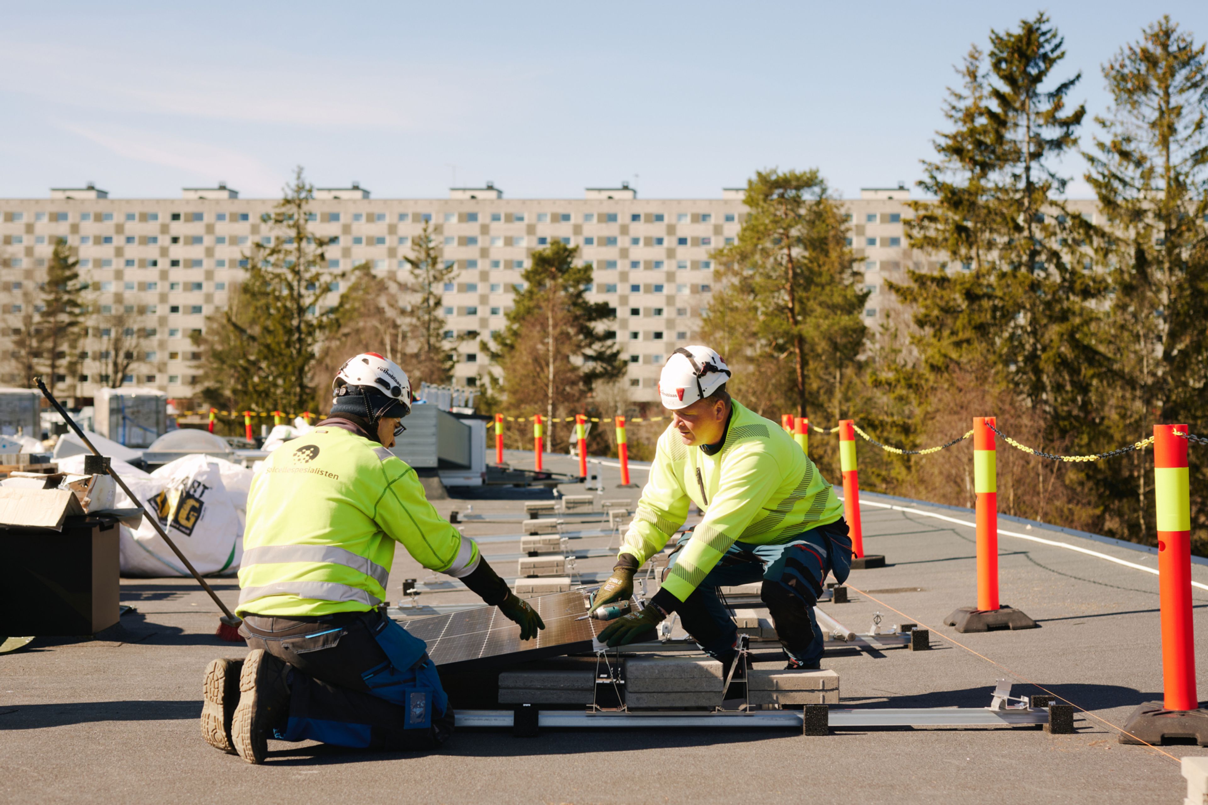 Bygningsarbeidere fra Enny installerer solceller på taket til Ammerudenga borettslag.