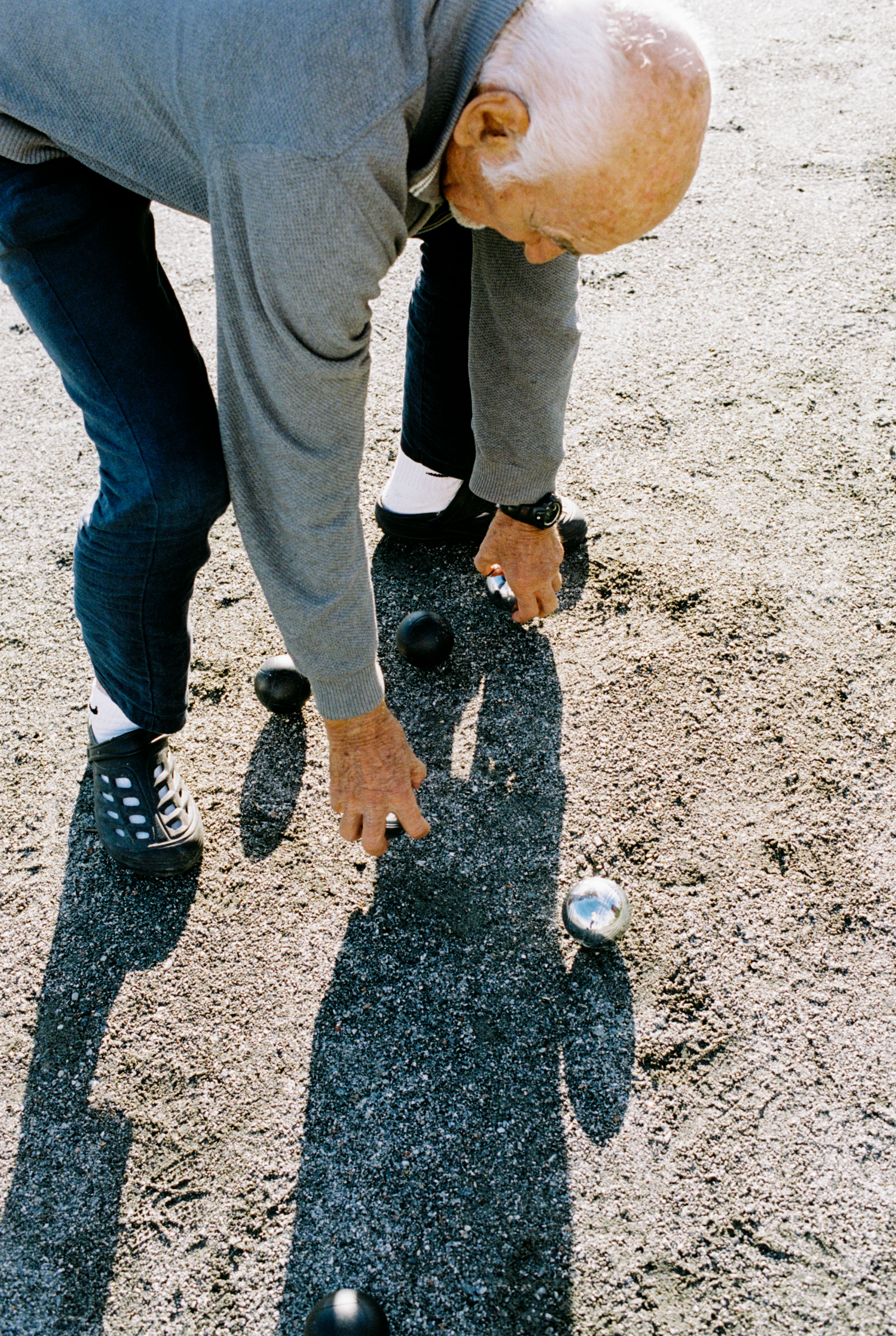 Reidar står og plukker opp petanque-kuler.