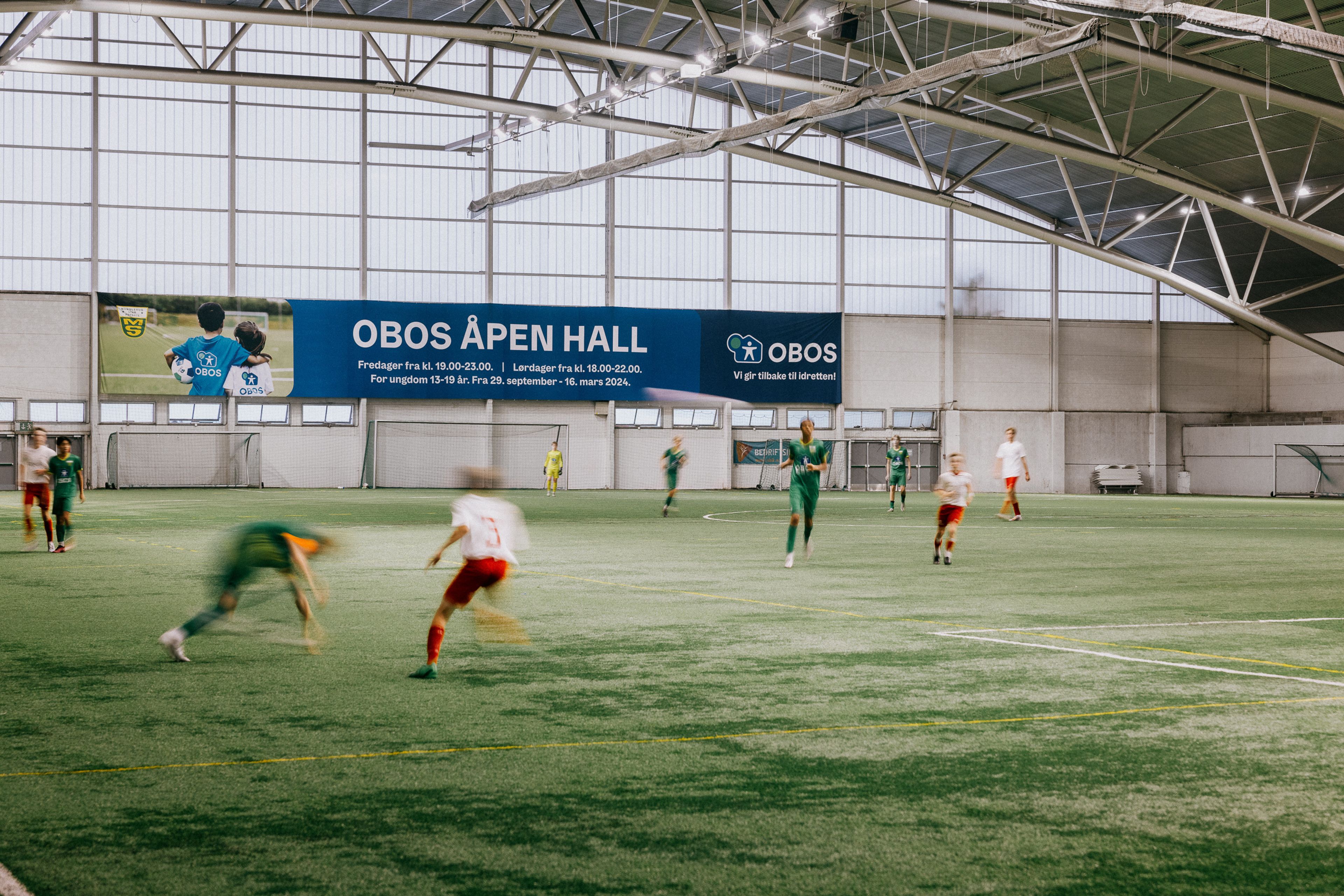 Flere ungdommer spiller fotball på kunstgresset inne i hallen