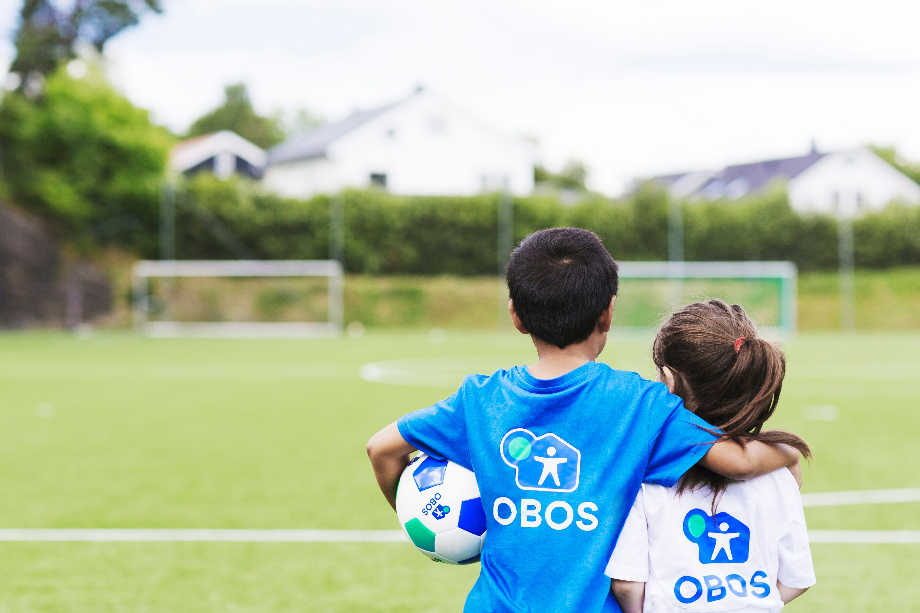 To barn i fotballdrakt på en fotballbane.