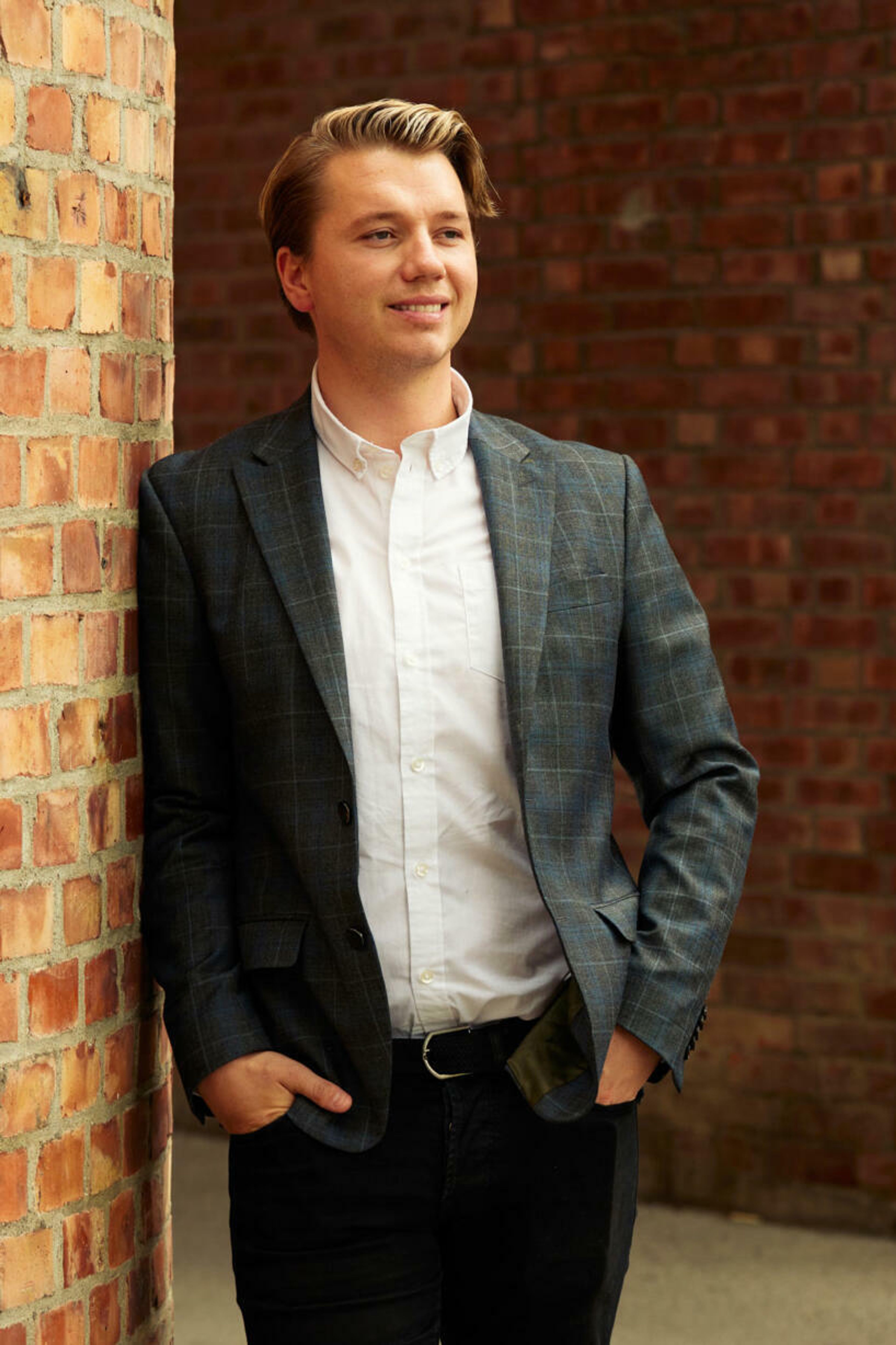 Bilde av Stian Strandum som lener seg mot en murvegg