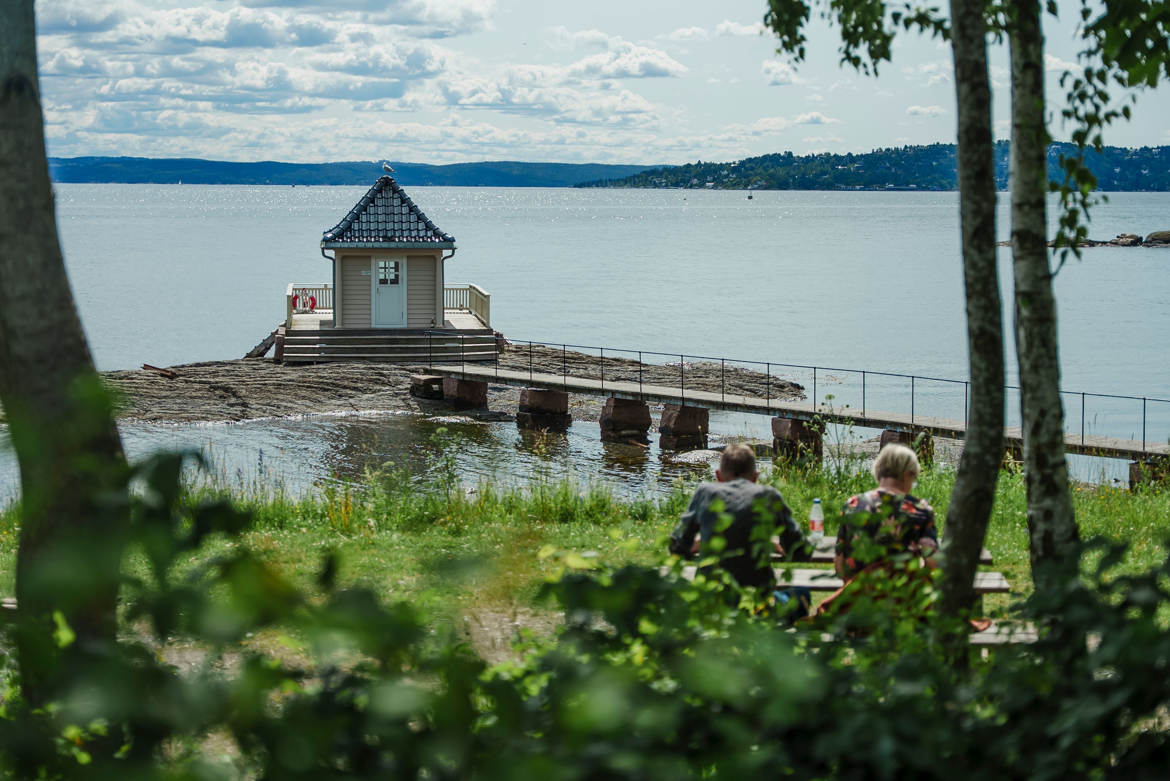 Personer på et piknikbord foran et båthus
