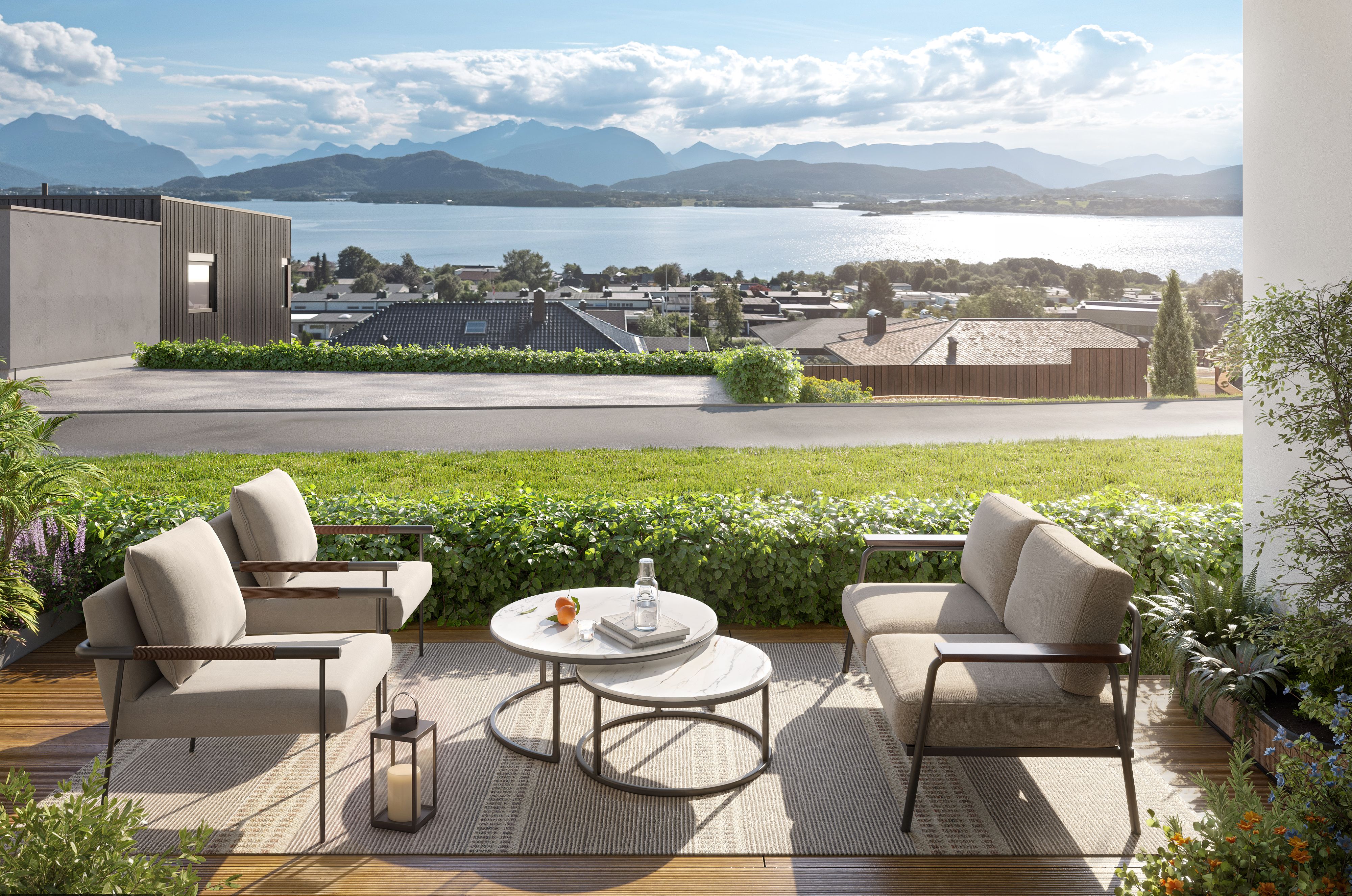 Uteplass utenfor første etasje i leilighetsbygg, med fjorden i bakgrunnen.